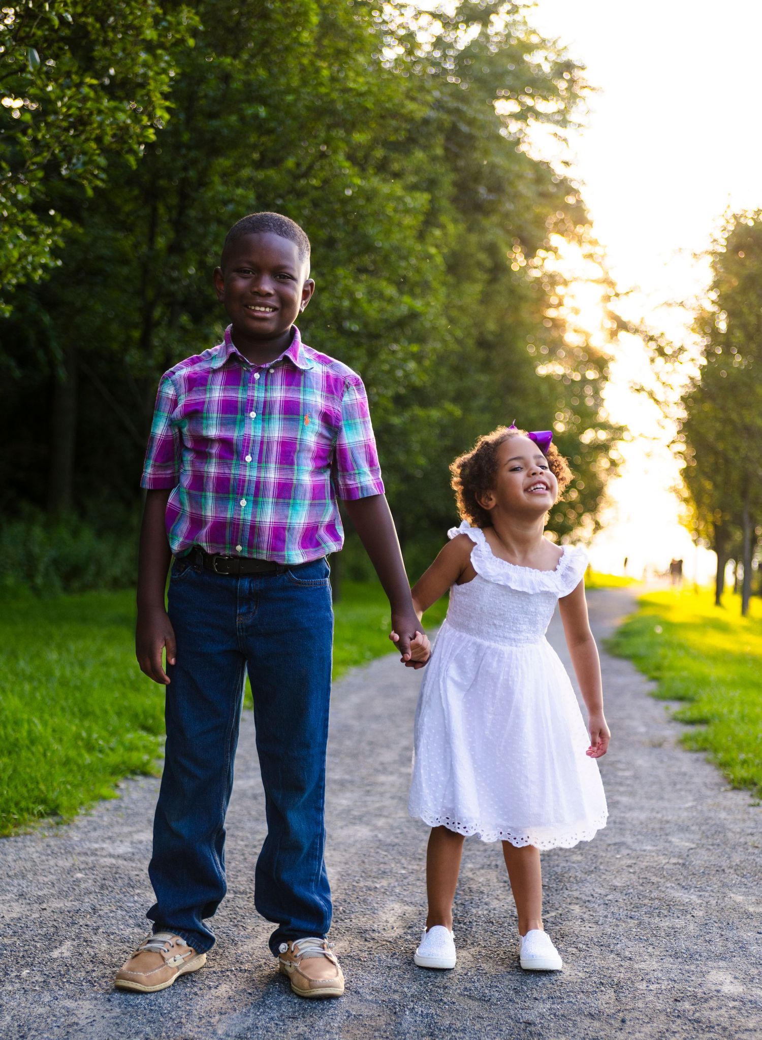 Two people in casual attire walking together on a sunny path.