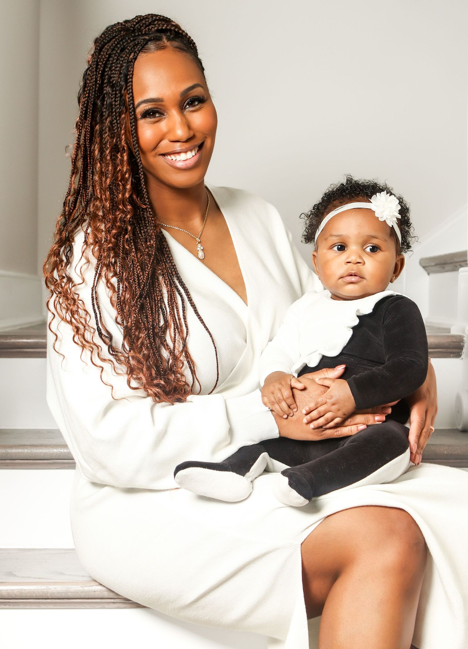 Heartwarming indoor portrait showing tender moment between parent and baby in matching white and black outfits.