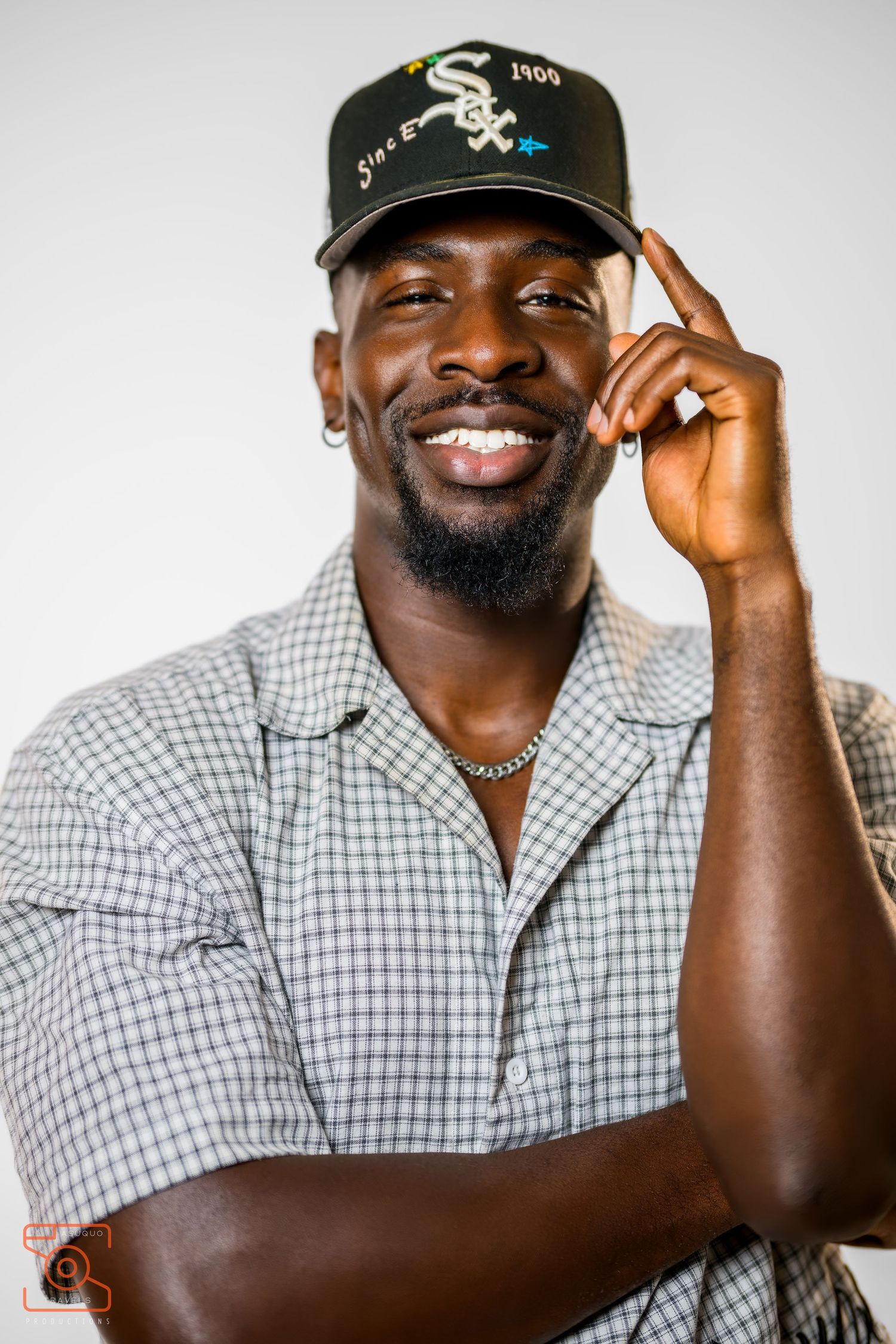 Person in checkered shirt and baseball cap making expressive poses against white background.
