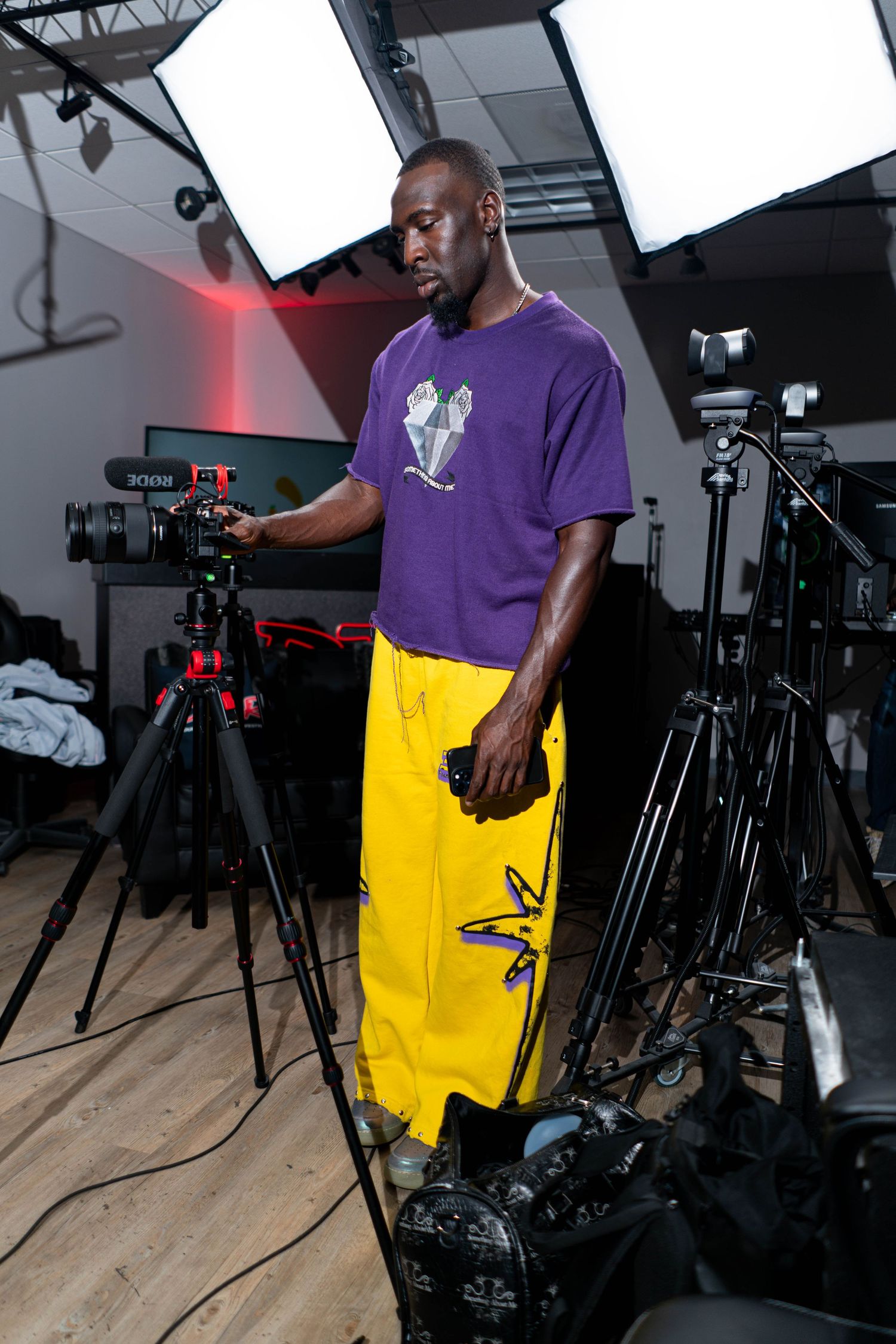 Photographer in purple shirt and yellow pants working with professional camera equipment.