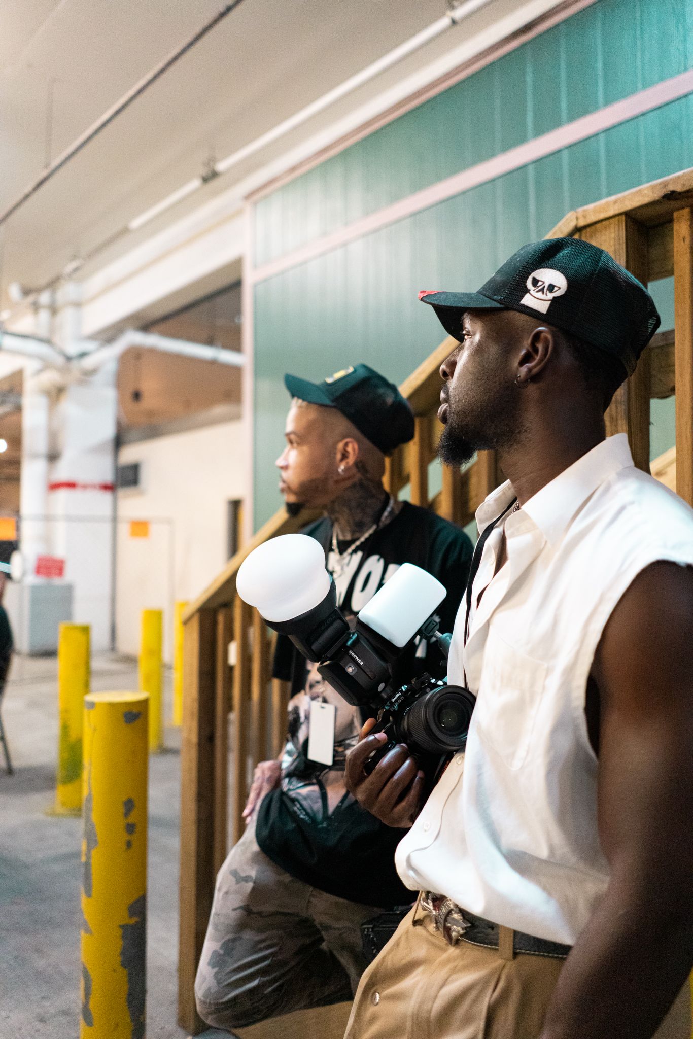 People with camera equipment in hallway during photo shoot.