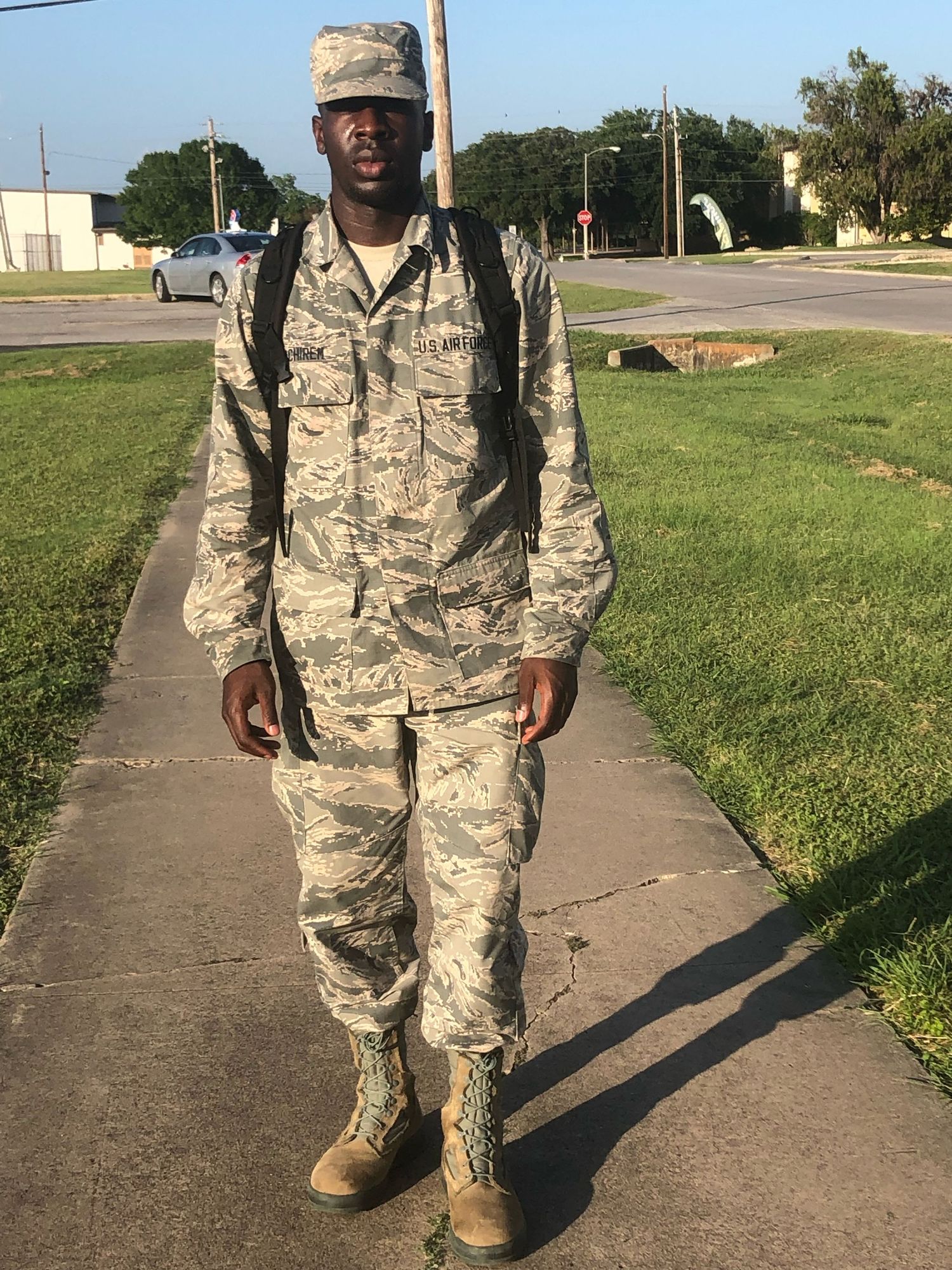 Person wearing military camouflage uniform walking on sidewalk path.