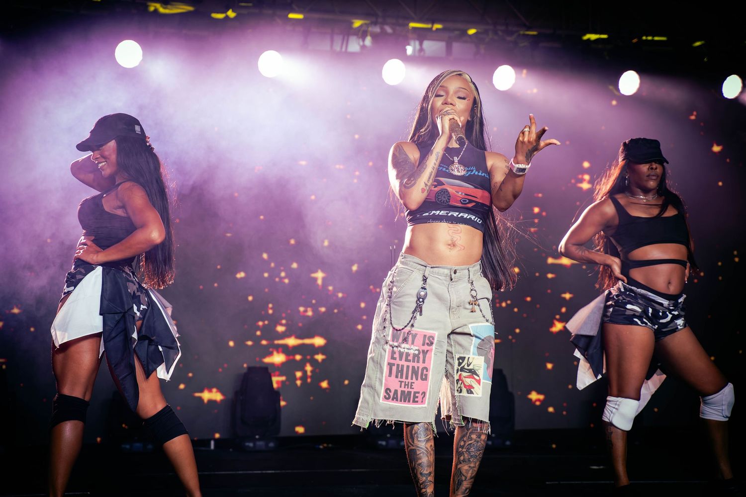 Dancers performing energetic routine on stage with purple lighting effects.