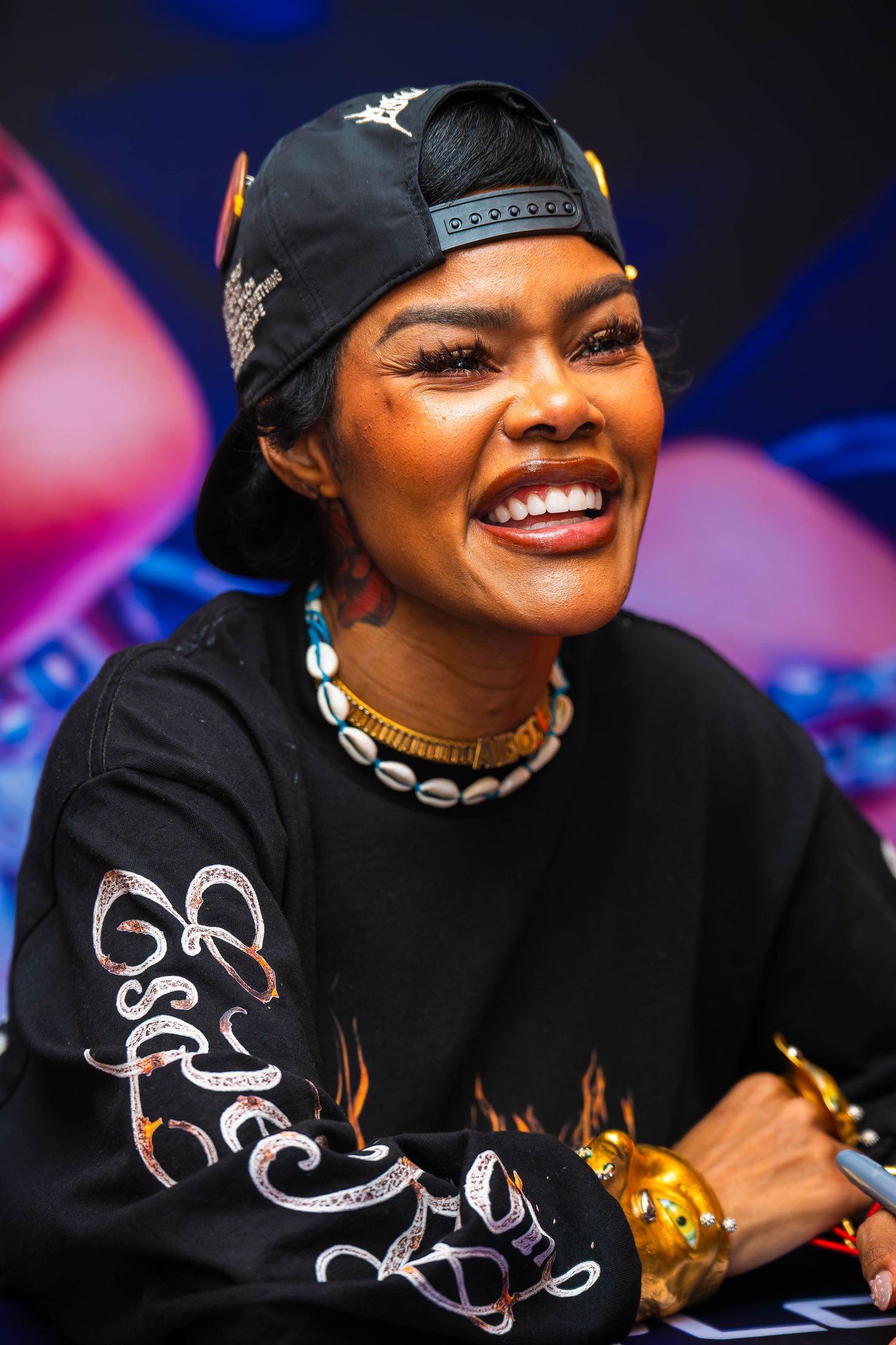 Artist wearing black cap and clothing smiles during meet and greet session.
