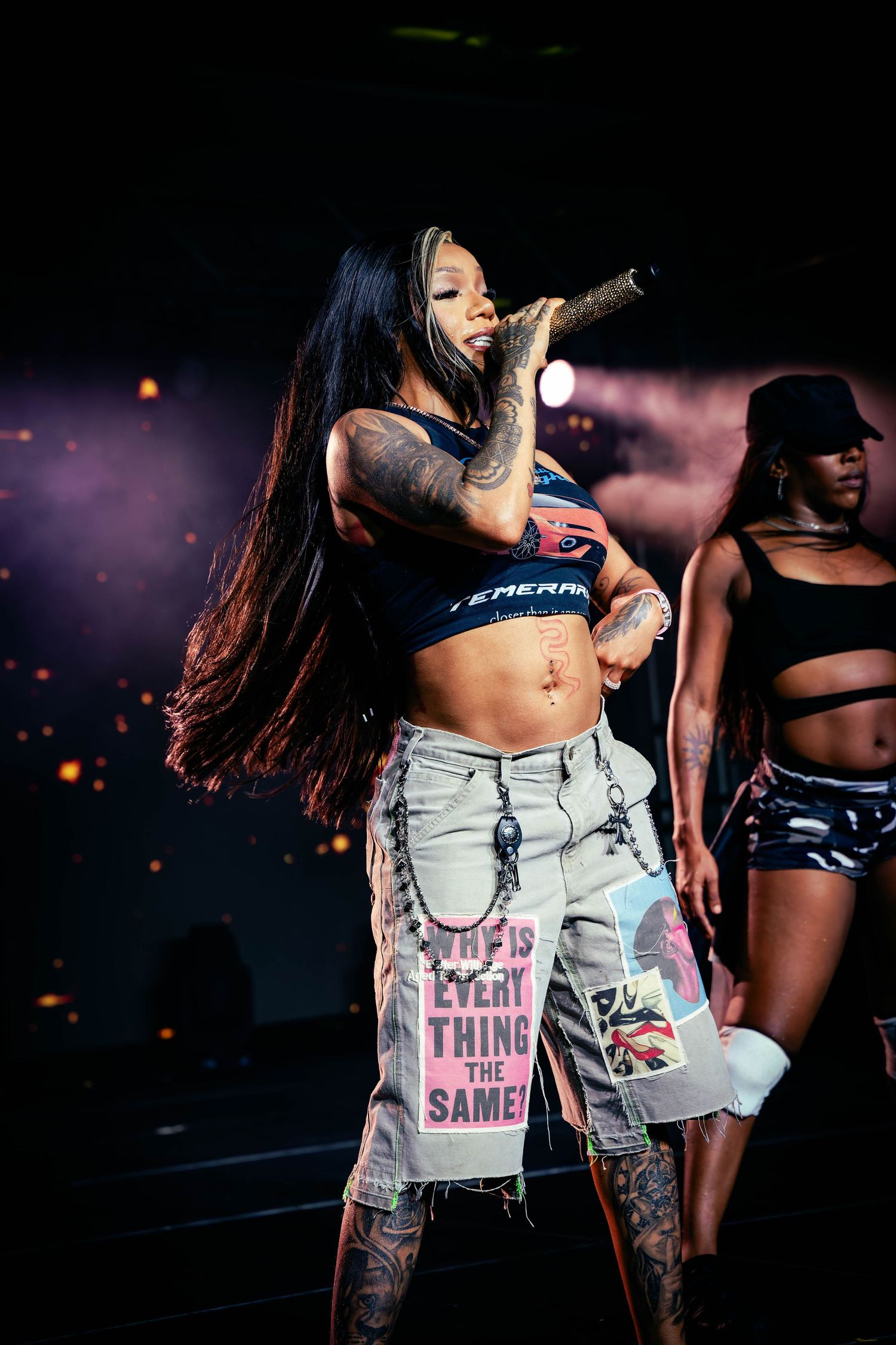 Dancers in crop tops and shorts performing choreographed routine on stage.