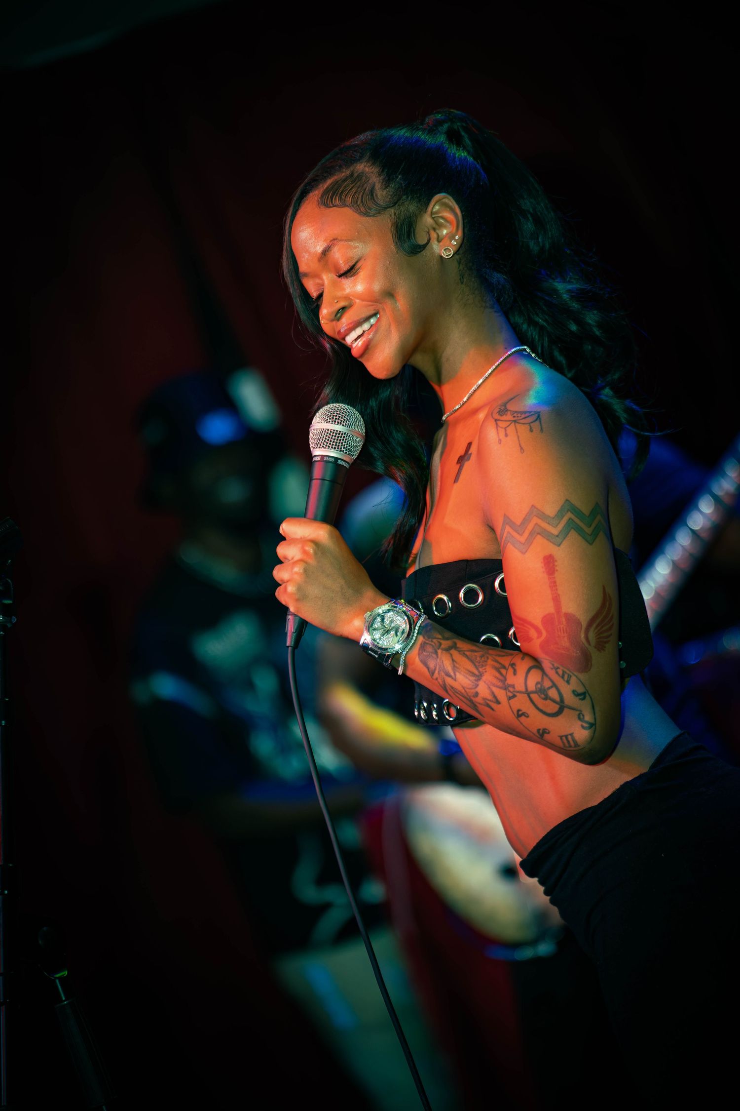 Dramatic low-light performance photo with microphone and stage lighting effects.