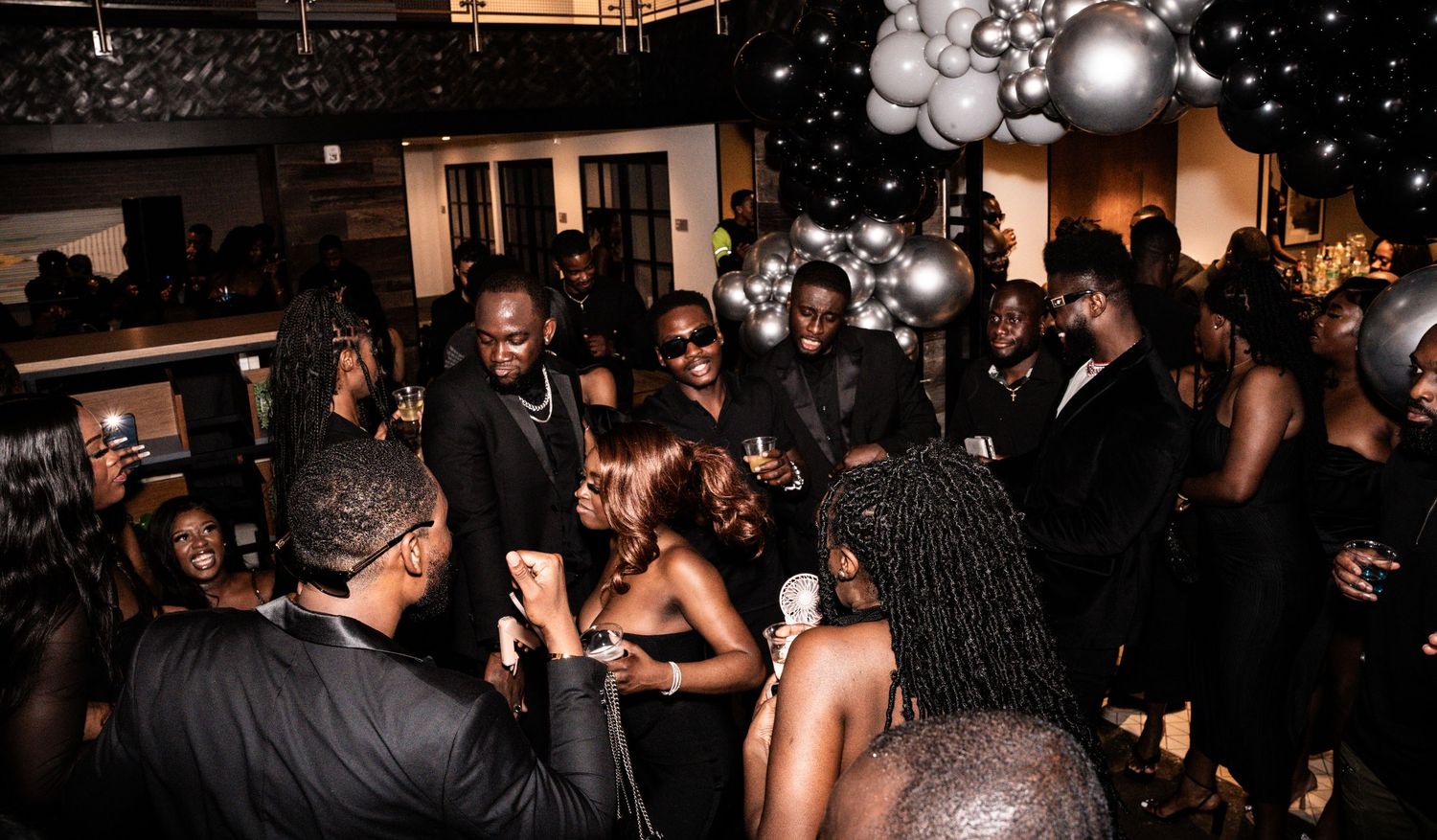 People dancing and celebrating at a lively party with sparkles and lights in a dark venue.