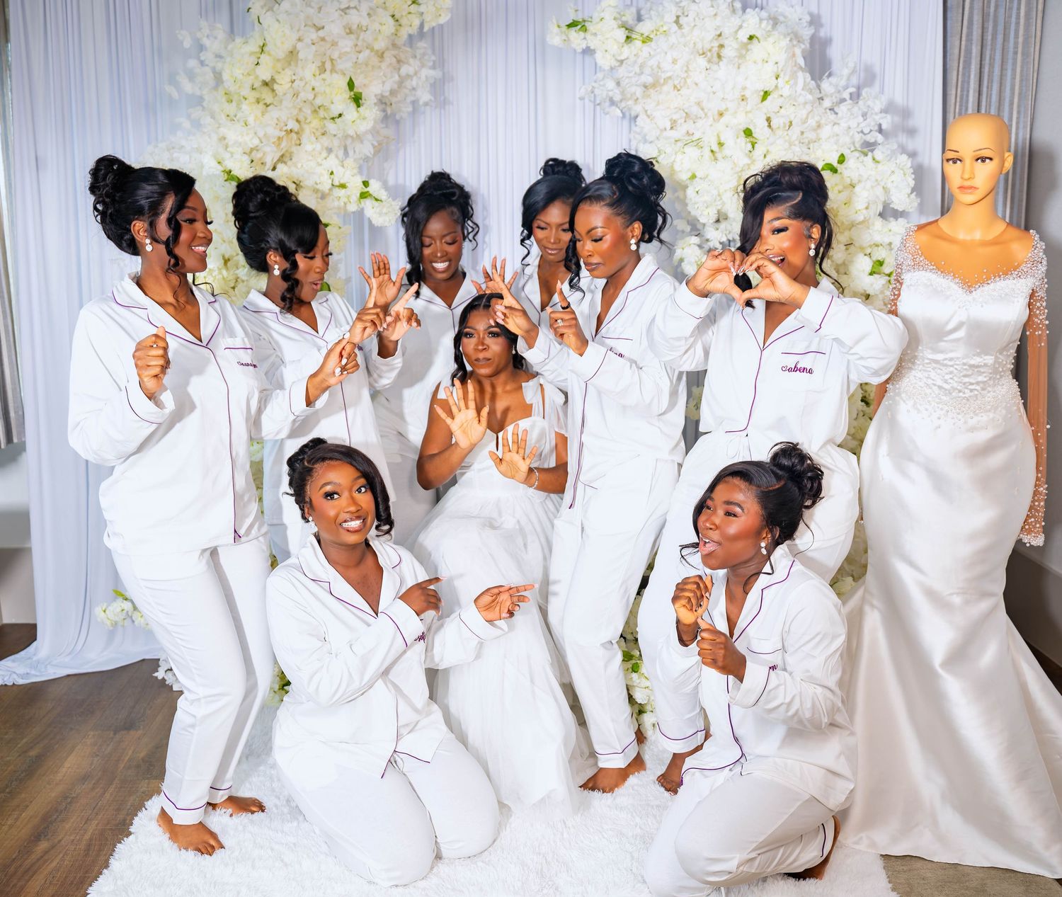 Wedding party members in white dresses pose playfully for a group photo.