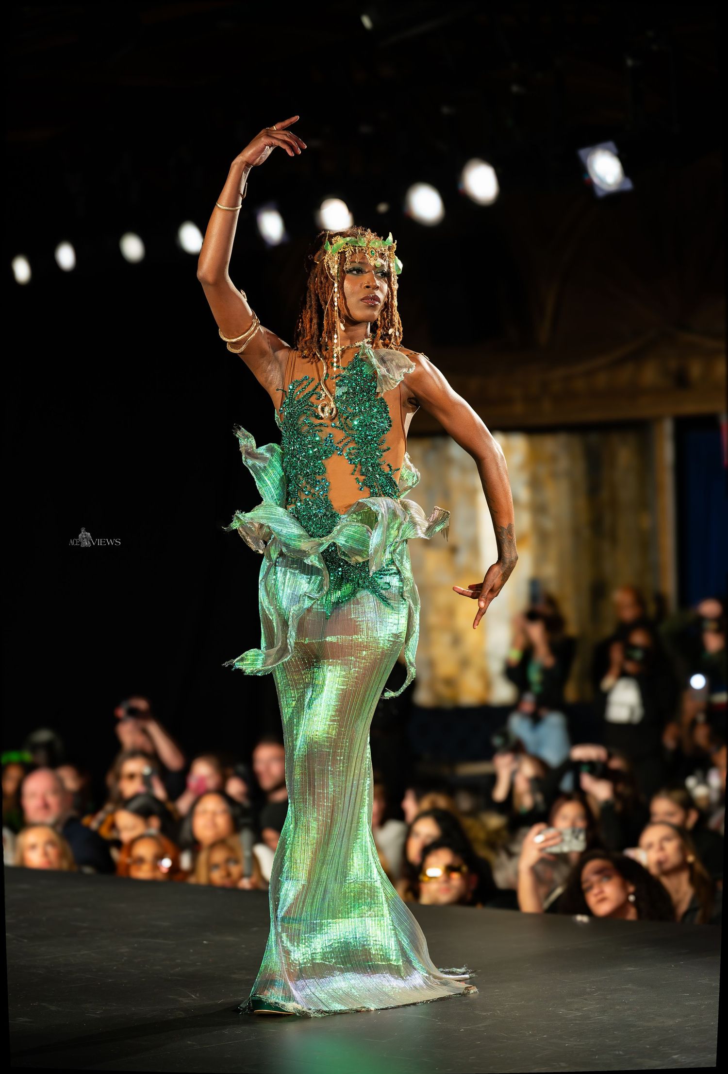Model showcases an ethereal mint green gown on an illuminated runway.