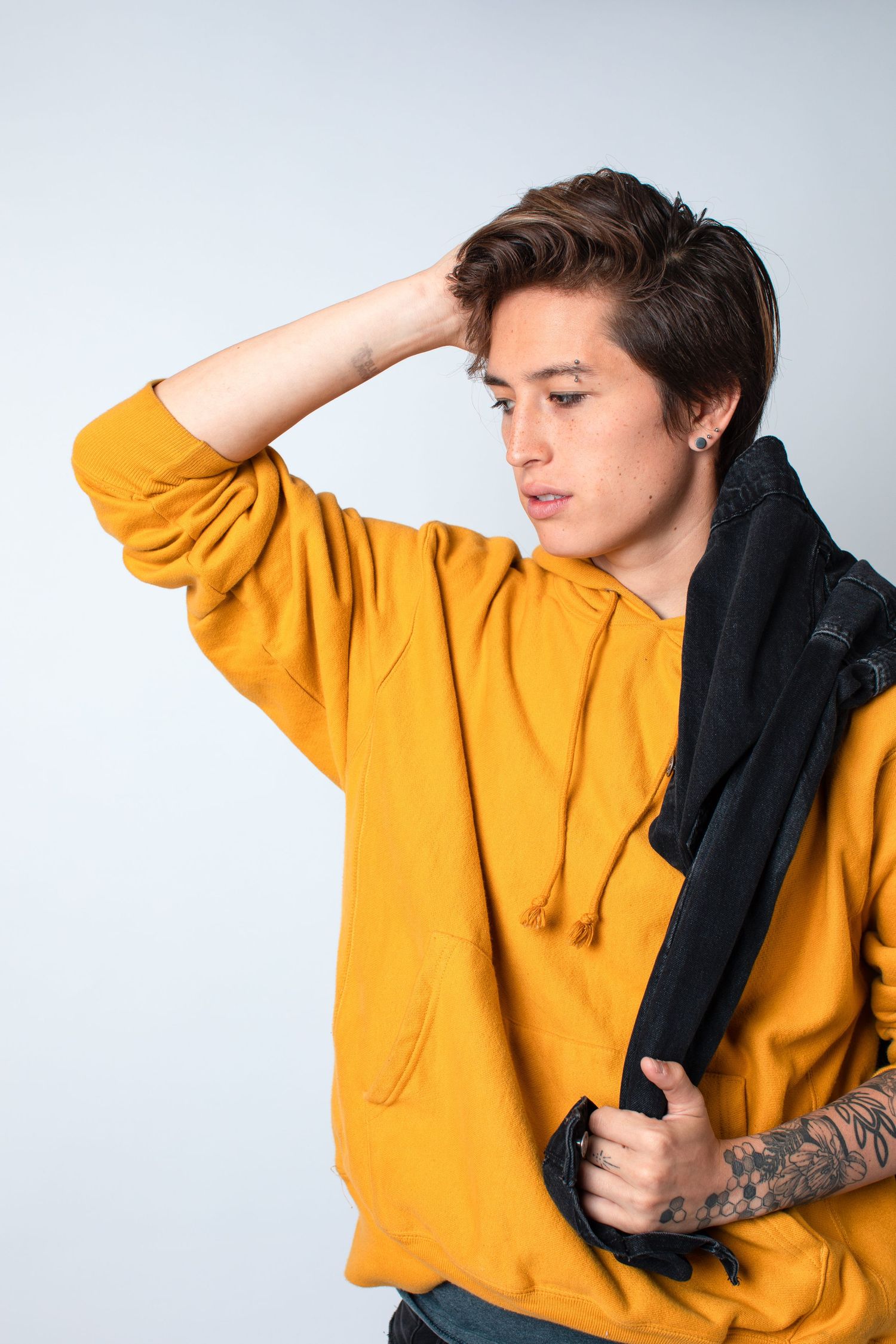 Artistic poses in bright yellow hoodie showing movement against white studio backdrop.