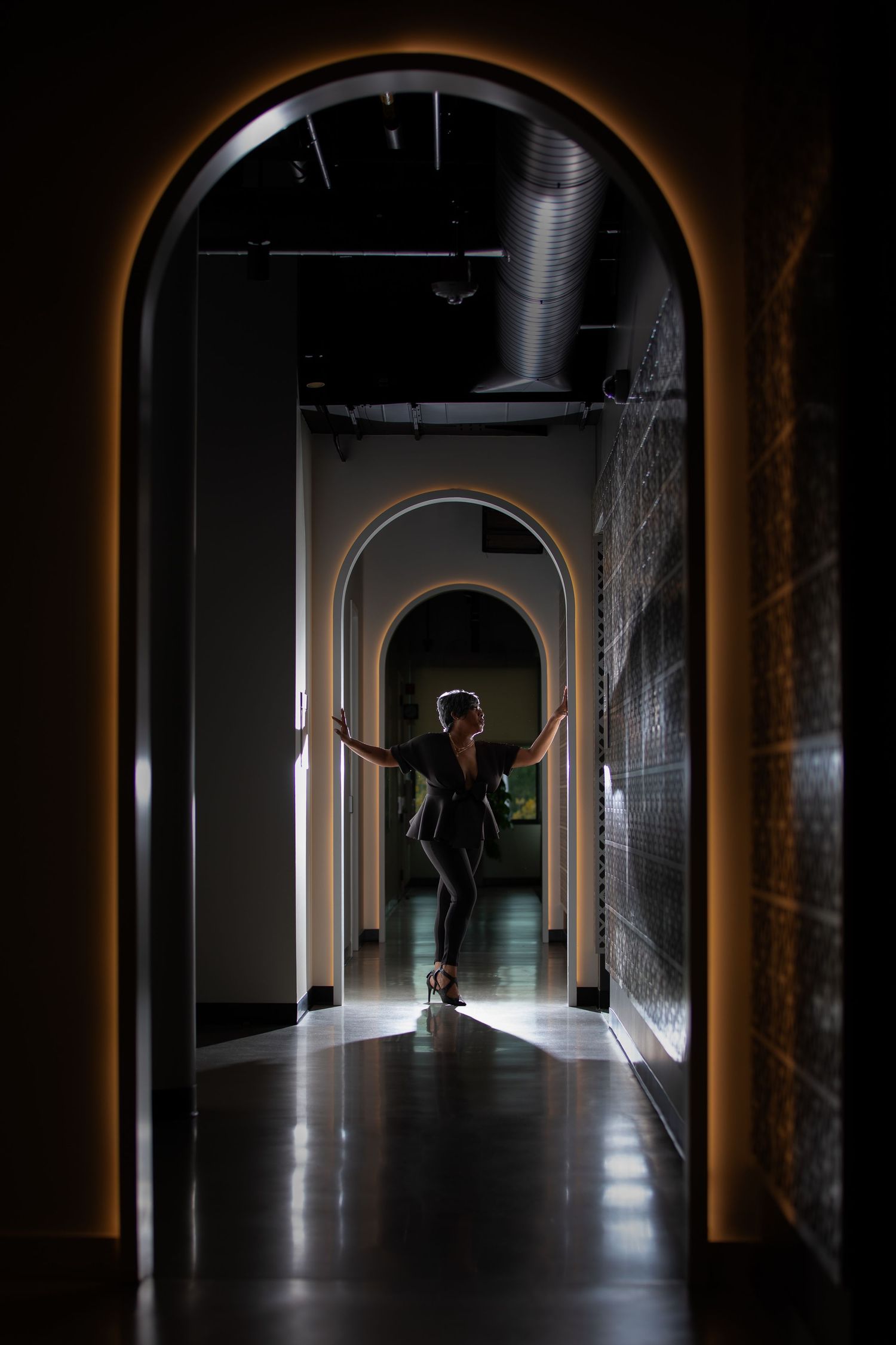 Silhouetted figure standing in a dimly lit arched corridor.