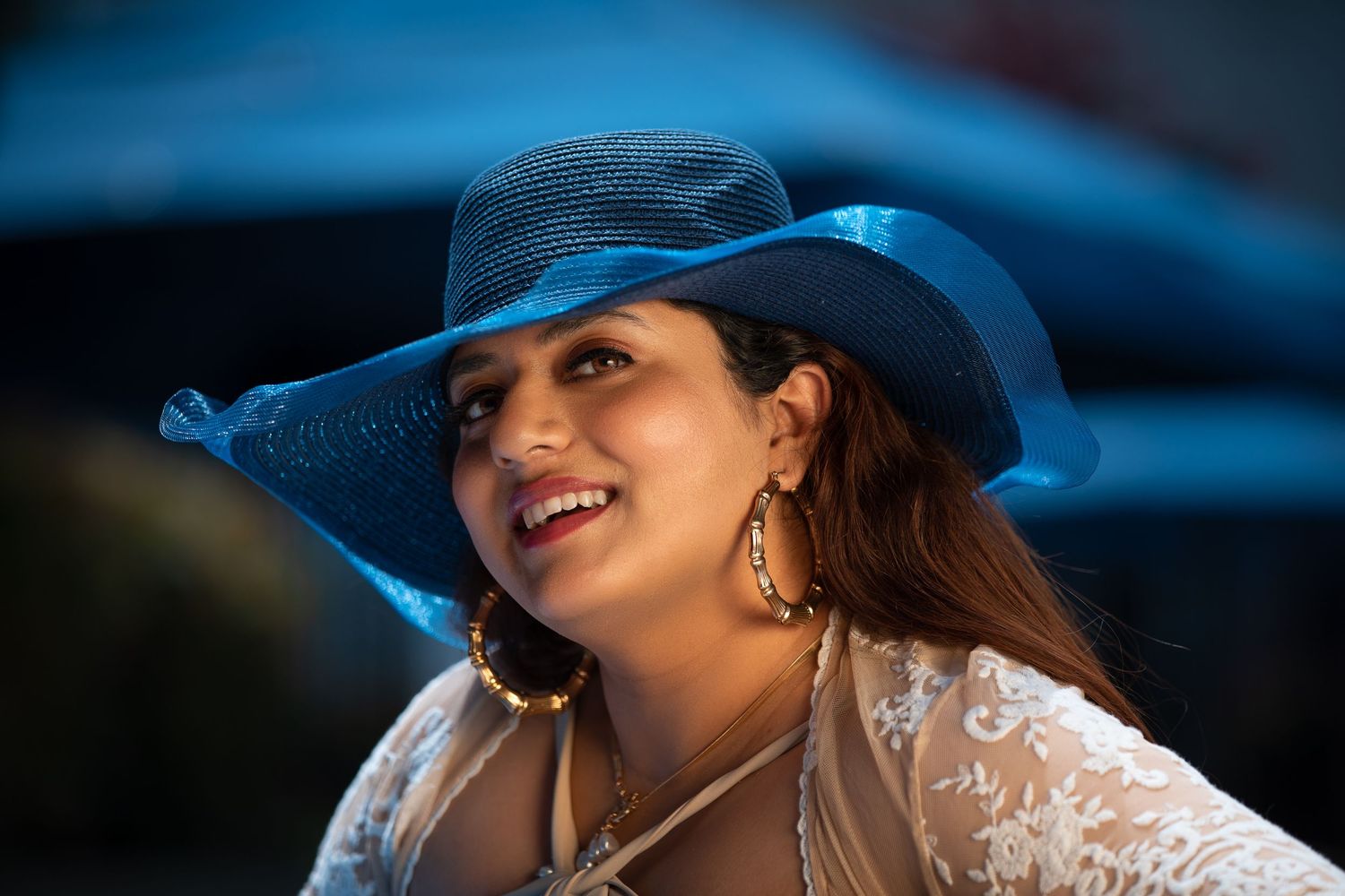 Outdoor portrait featuring a bright blue sunhat and delicate lace coverup with statement earrings.