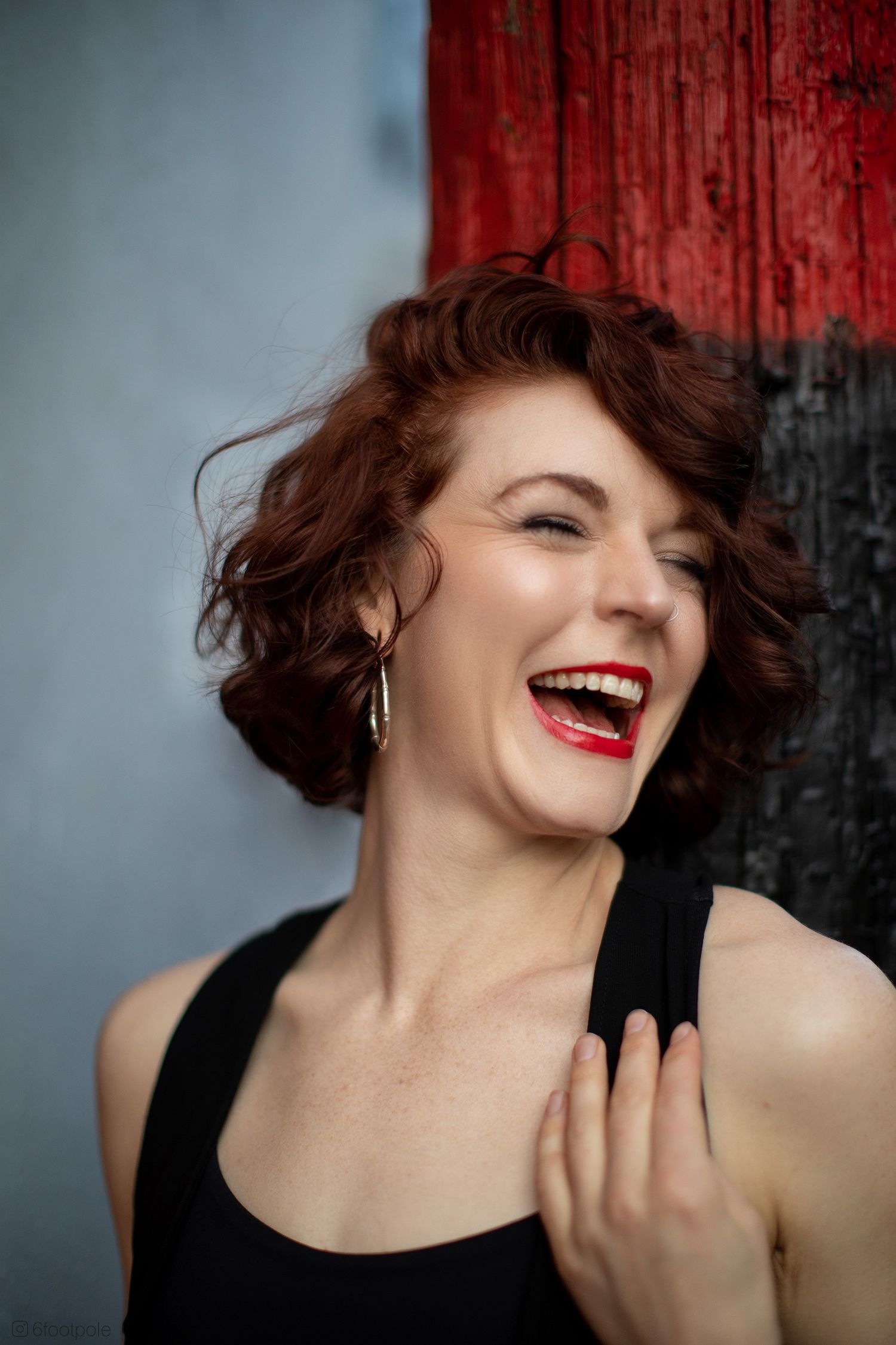 Expressive dance portrait with dramatic red backdrop and joyful movement.