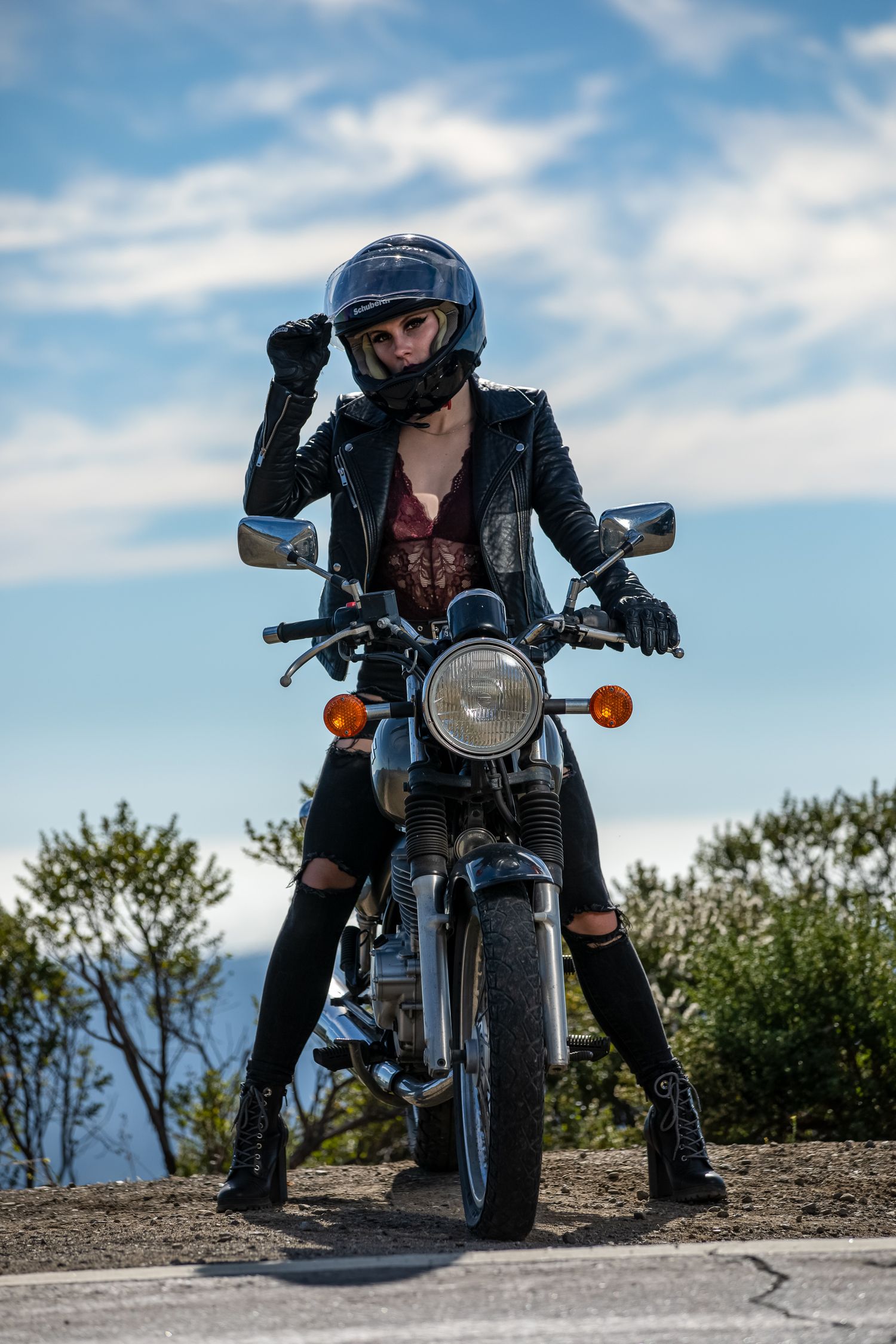 Low-angle shot of a motorcycle on a mountain trail with blue sky overhead.