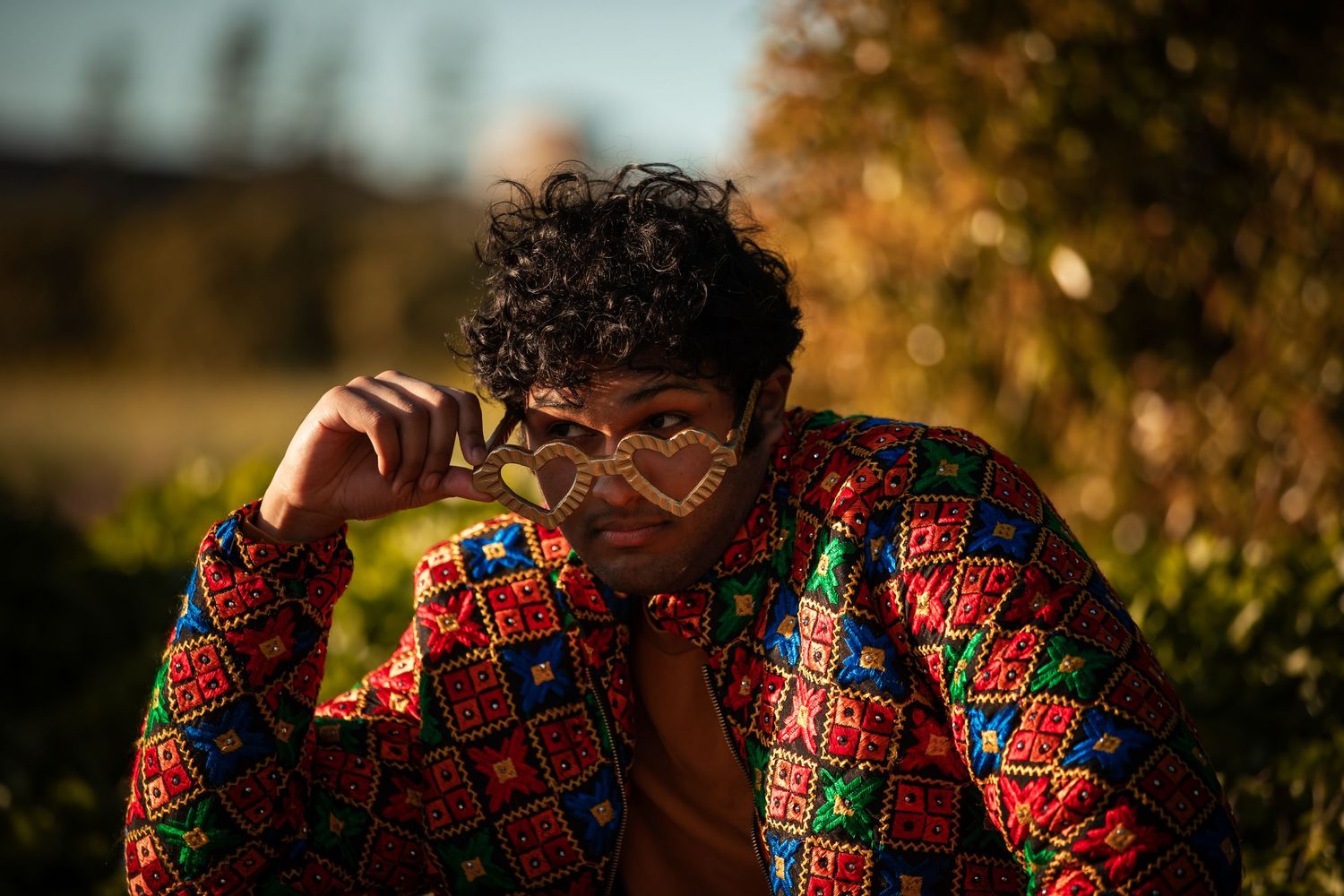 Figure in bright patterned clothing photographed against natural outdoor backdrop.