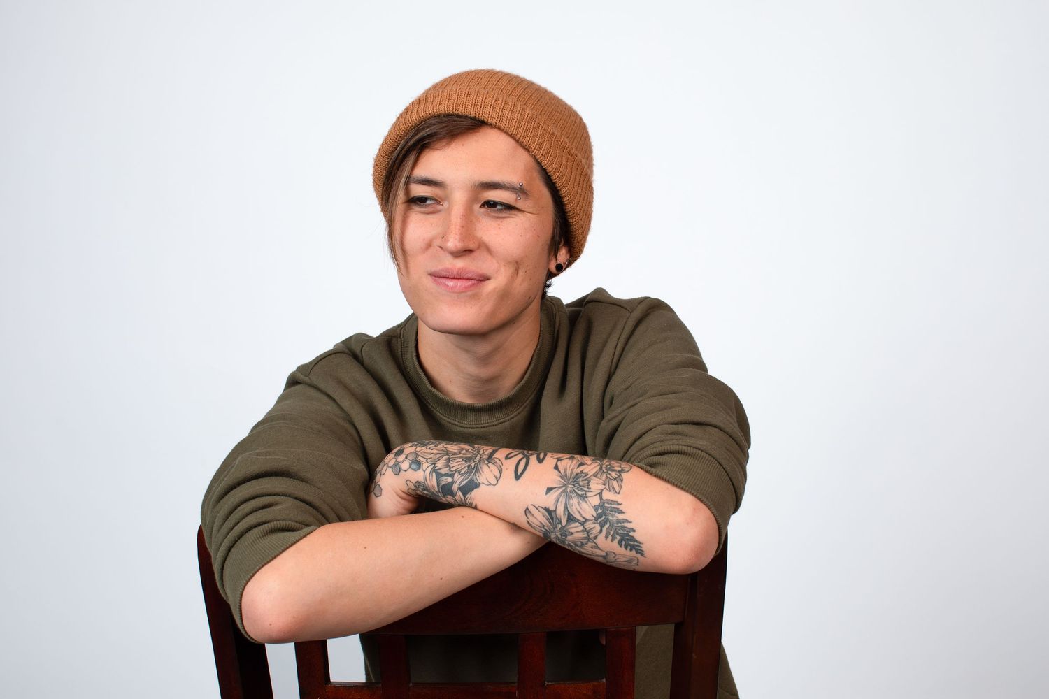 Casual portrait series in brown beanie and olive hoodie against white background.