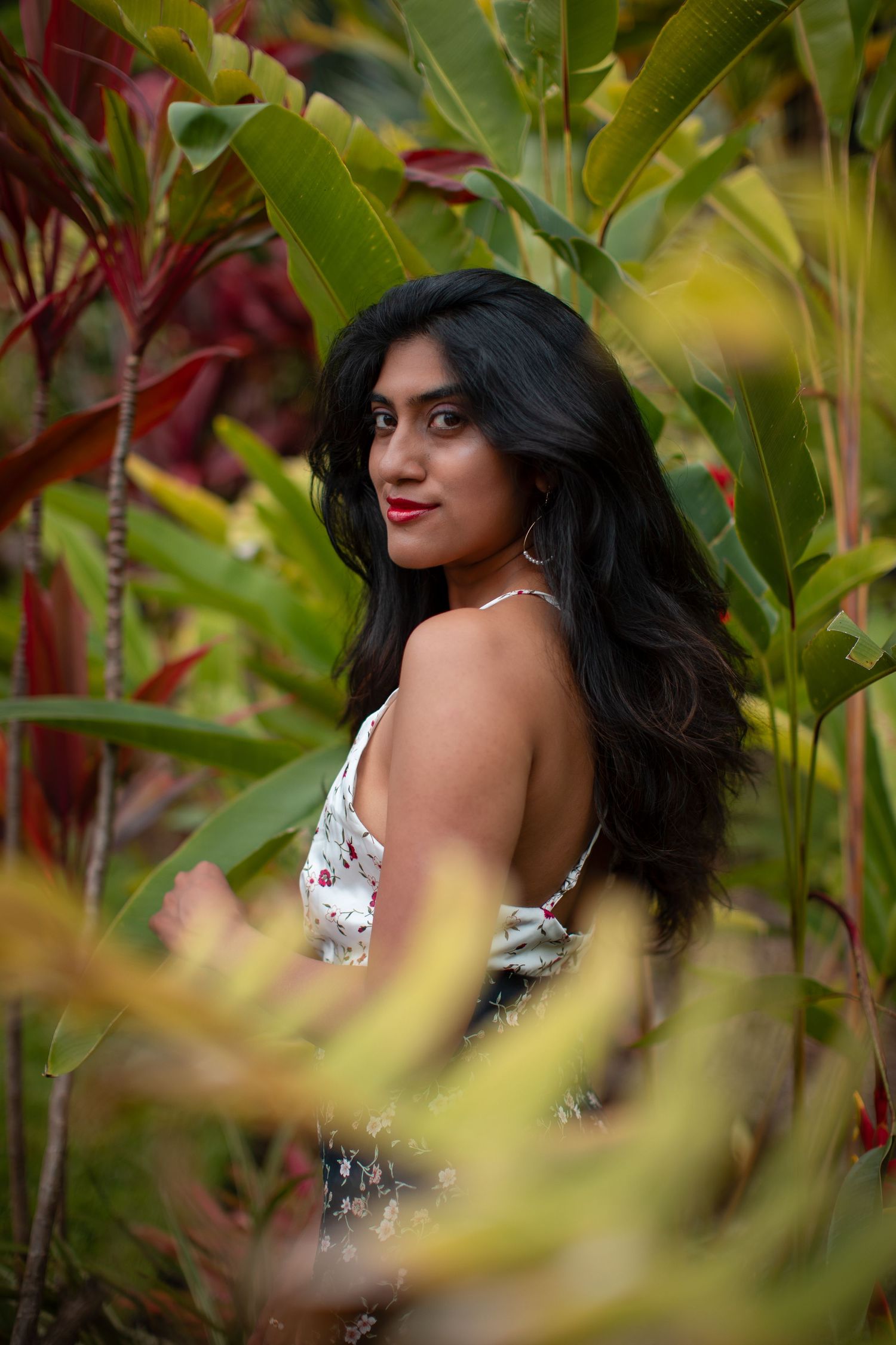 Portrait in a lush garden setting with tropical foliage and flowers.