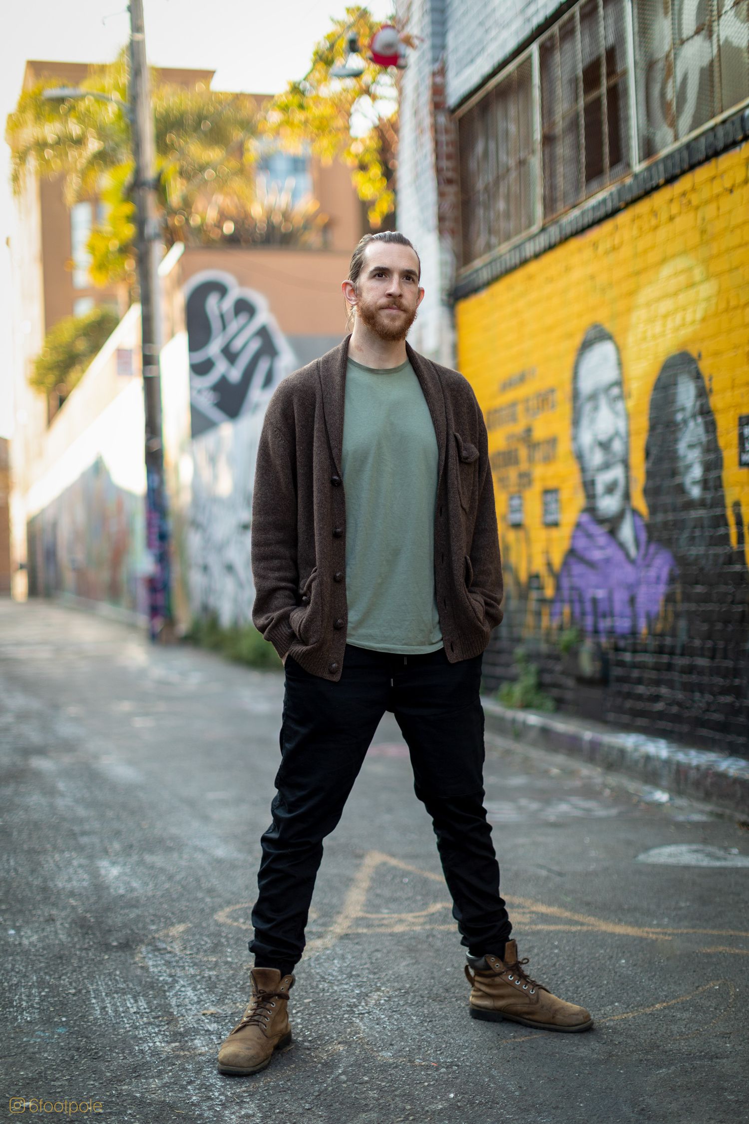 Urban fashion shoot with casual outfit against yellow graffiti wall in alleyway.
