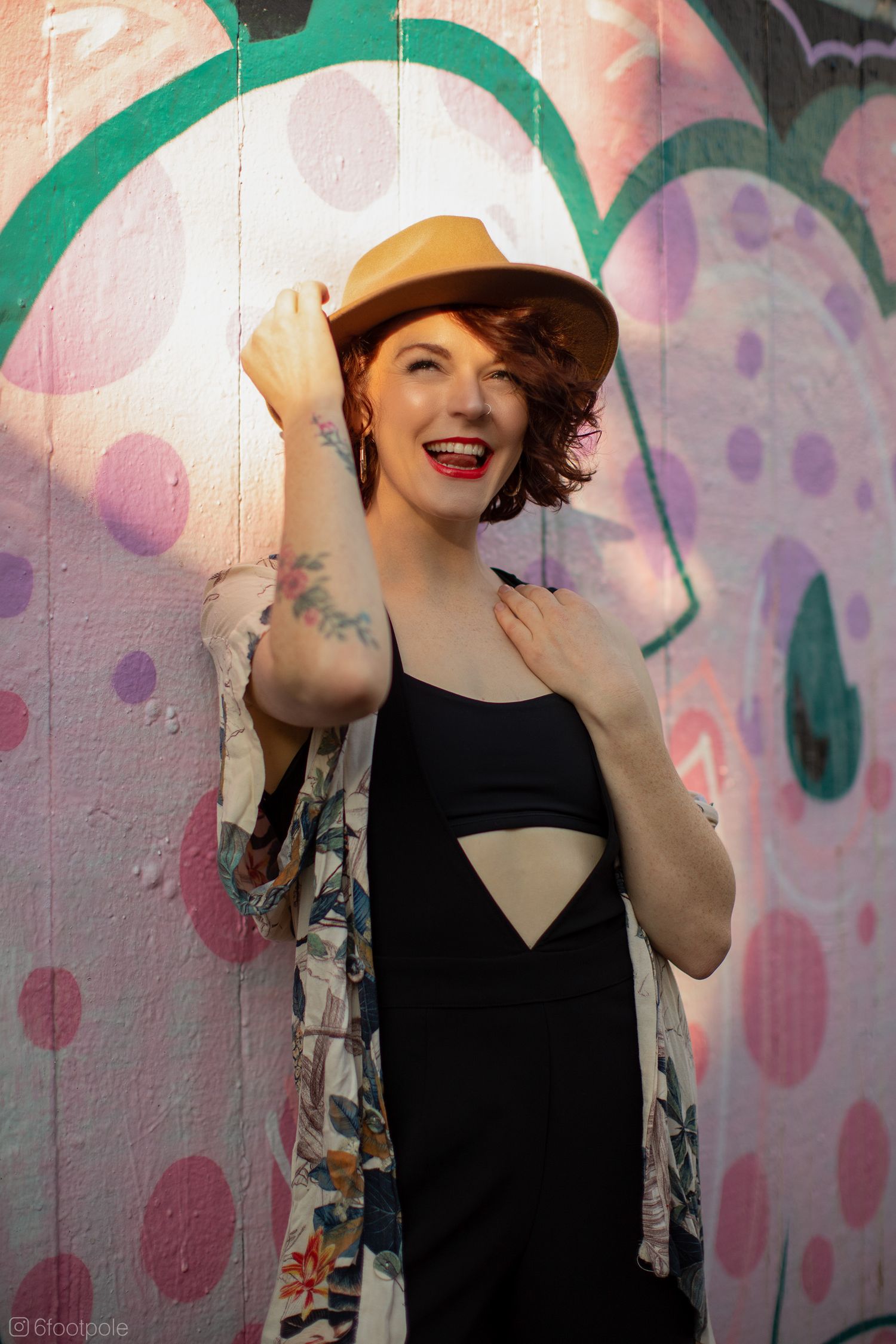 A sequence of photos showing someone in a black dress and tan hat posing against a colorful polka dot wall background.