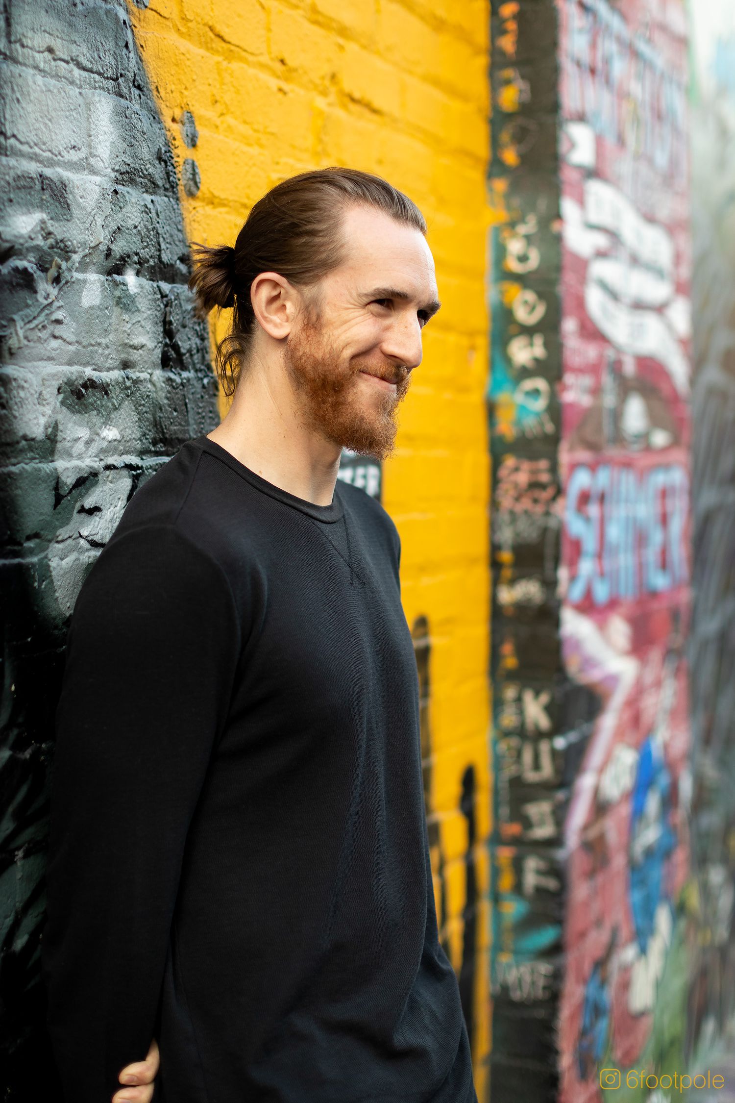 Artistic portrait against yellow and gray graffiti wall showing urban fashion style.