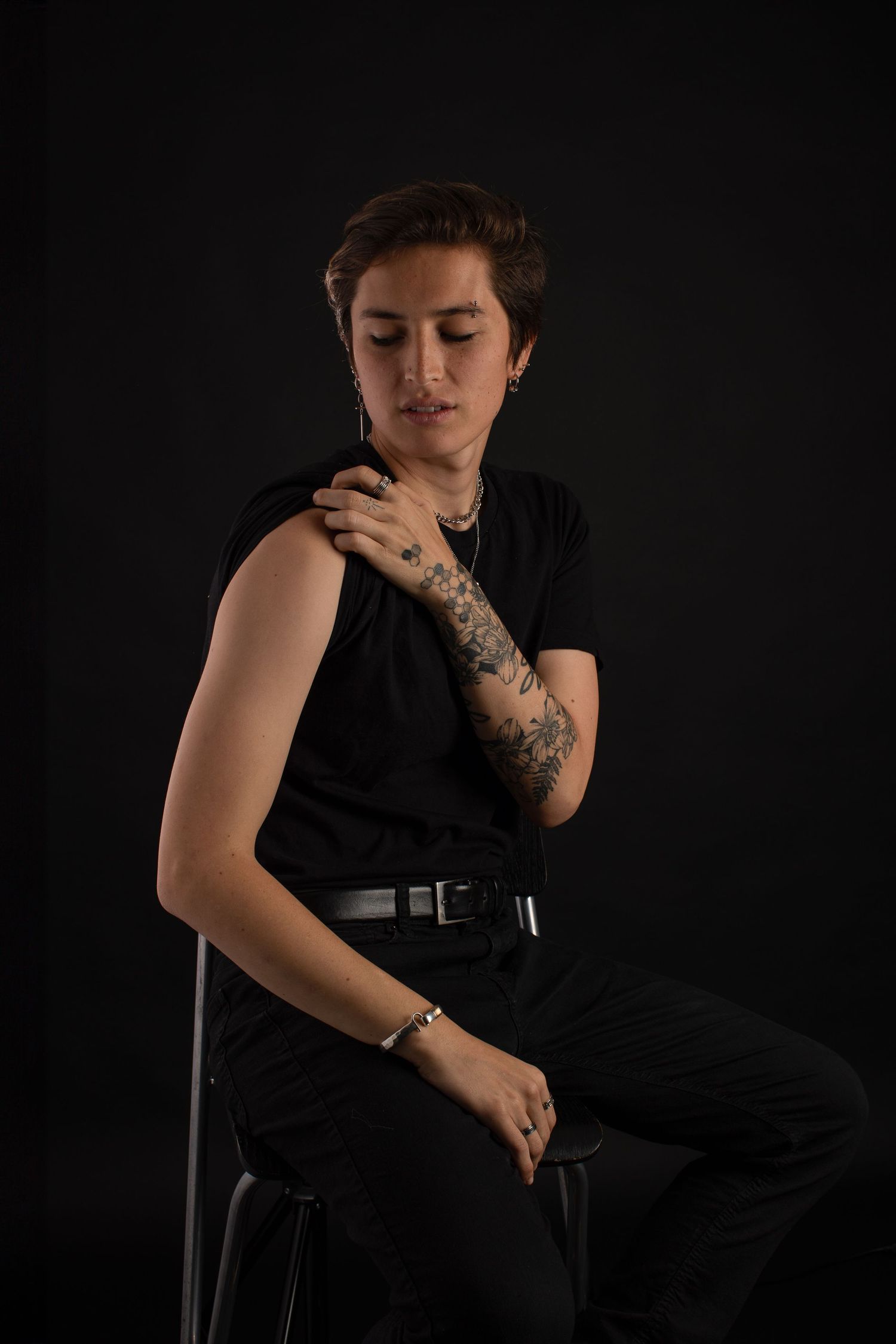 Dramatic low-key portraits in black attire against dark background showing tattoo details.
