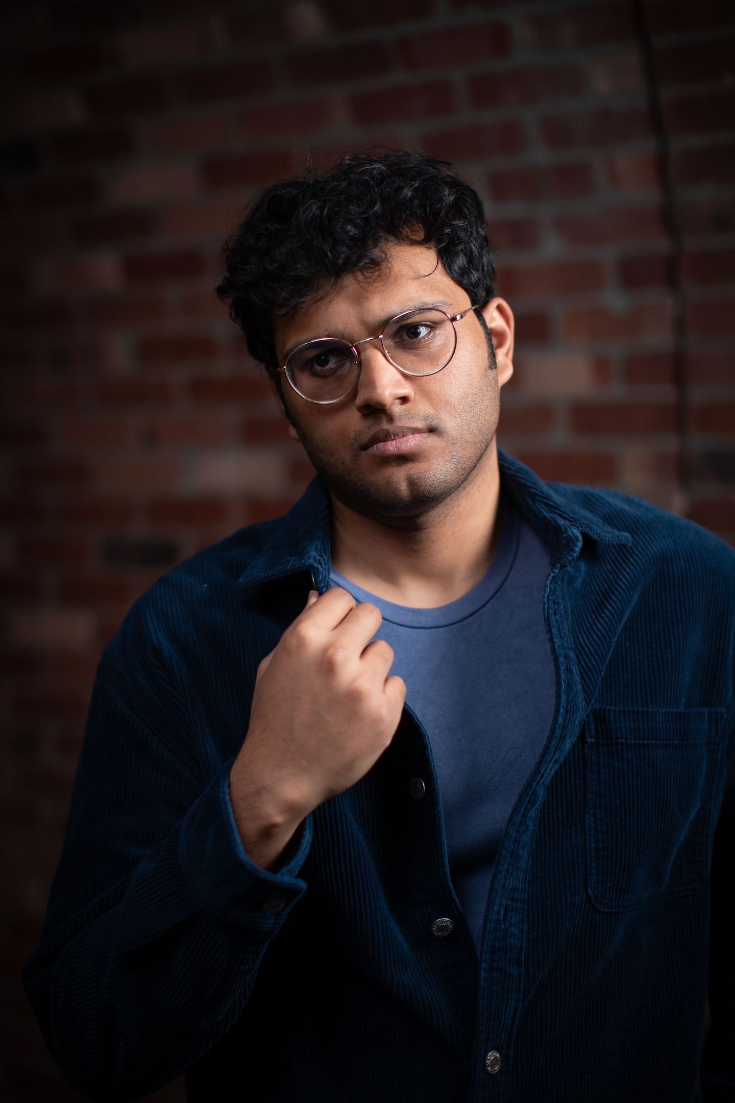 Portrait series showing contemplative poses against a brick wall backdrop in dark lighting.