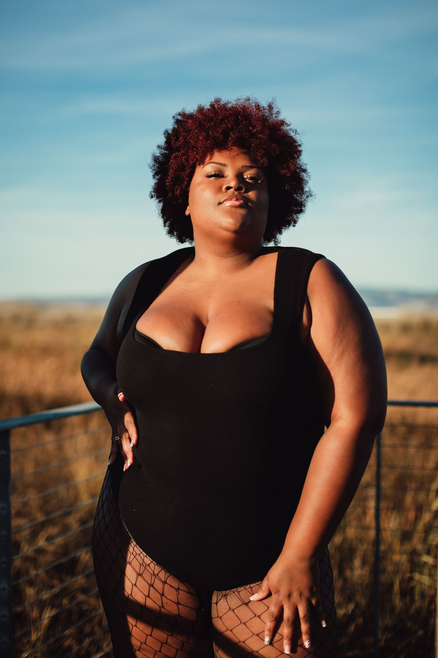 Fashion photography session featuring black attire and fishnet accessories on a wooden deck.