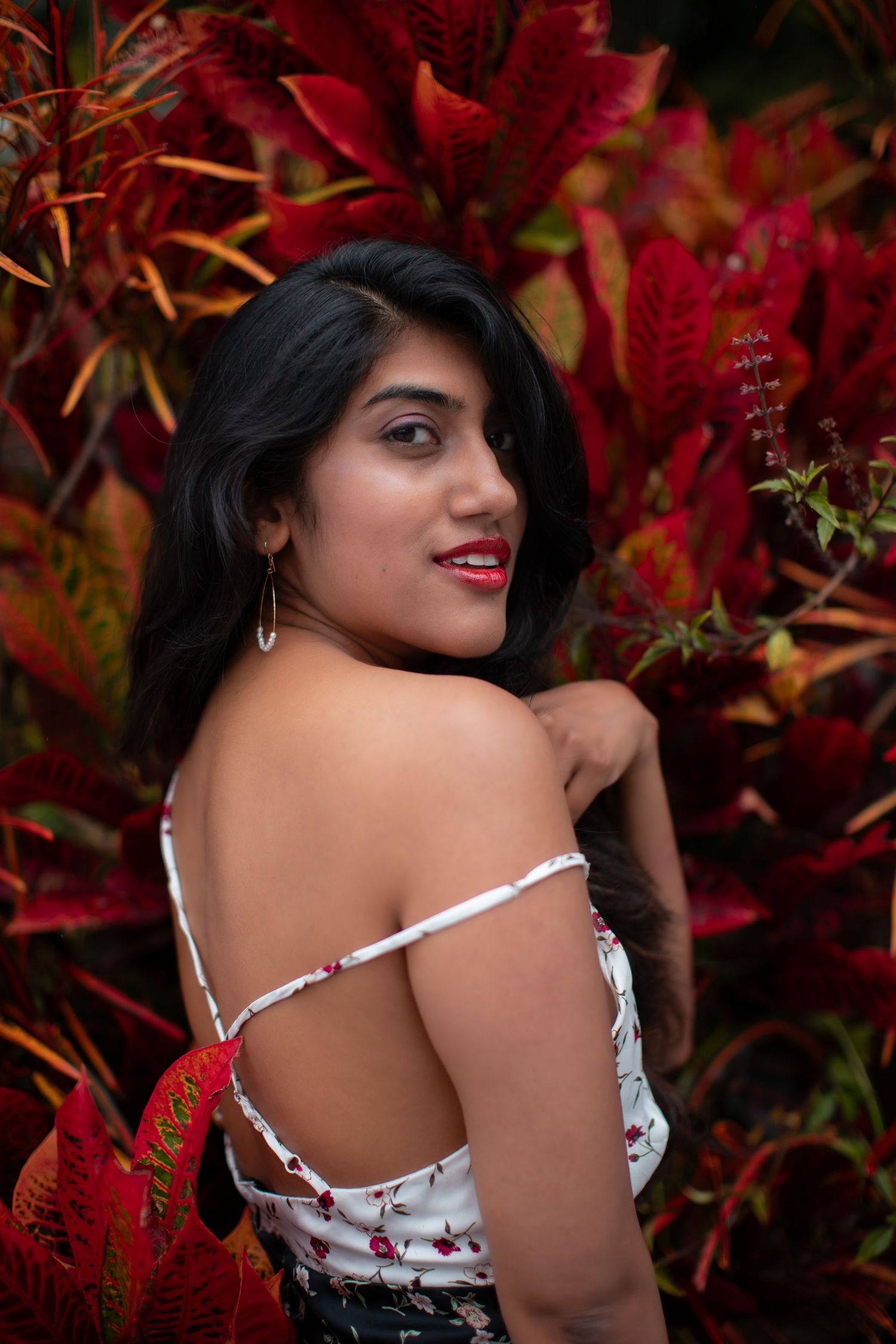 Artistic autumn photography with red foliage and white floral dress details.