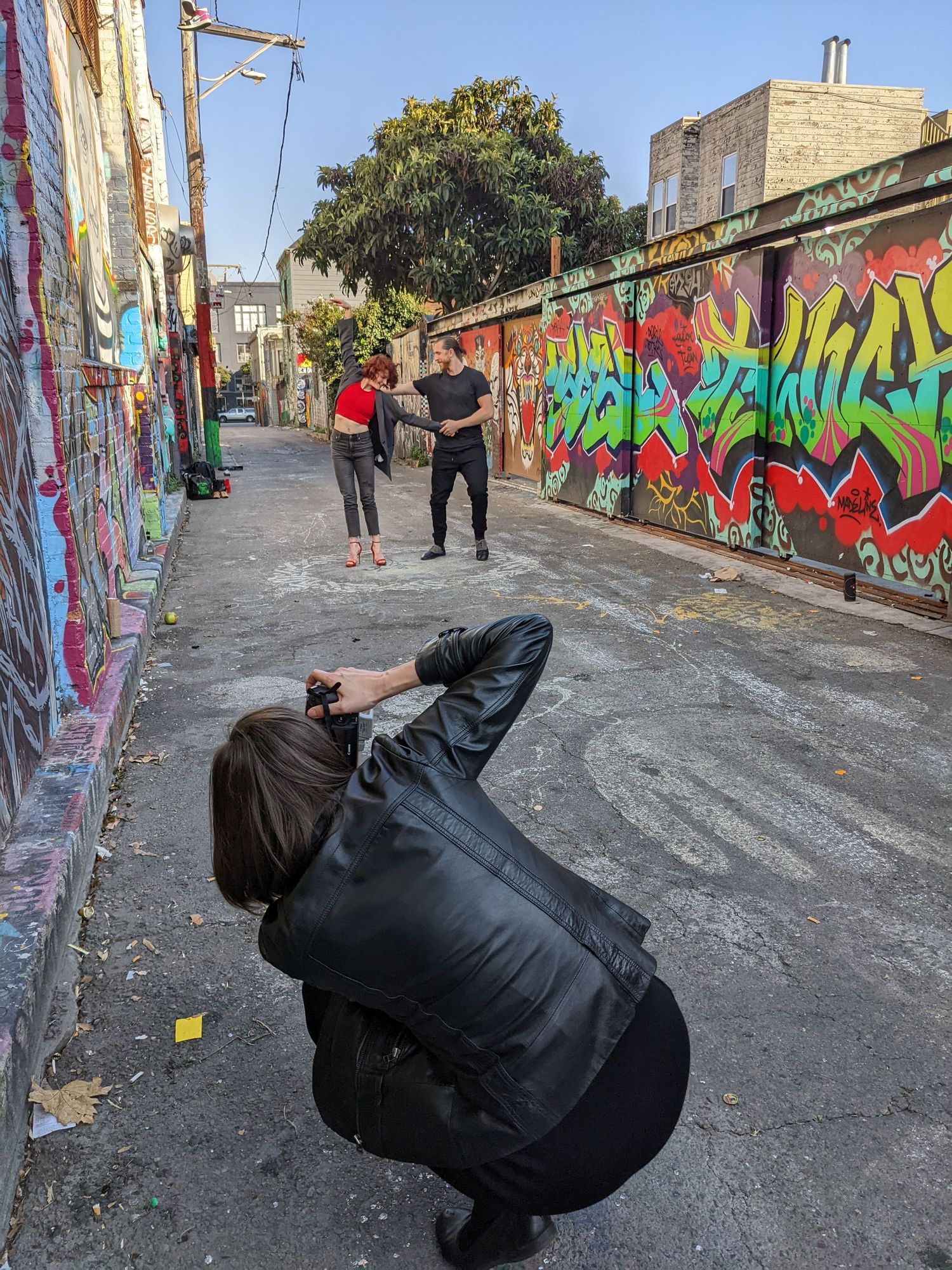 A sequence of five photos showing someone in black clothing performing a backflip against a graffiti-covered wall.
