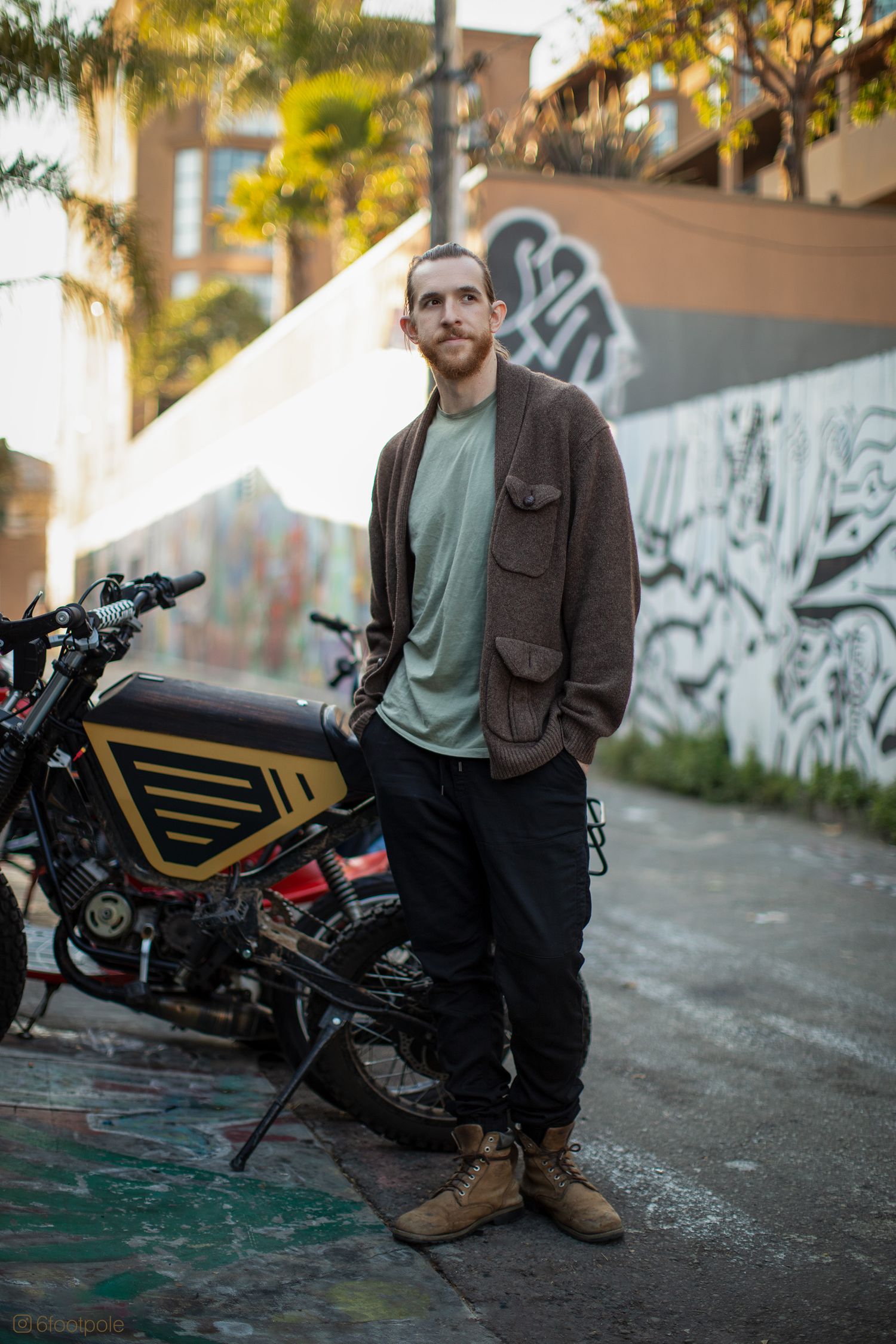 Urban motorcycle portrait against graffiti wall with warm autumn lighting and custom bike.
