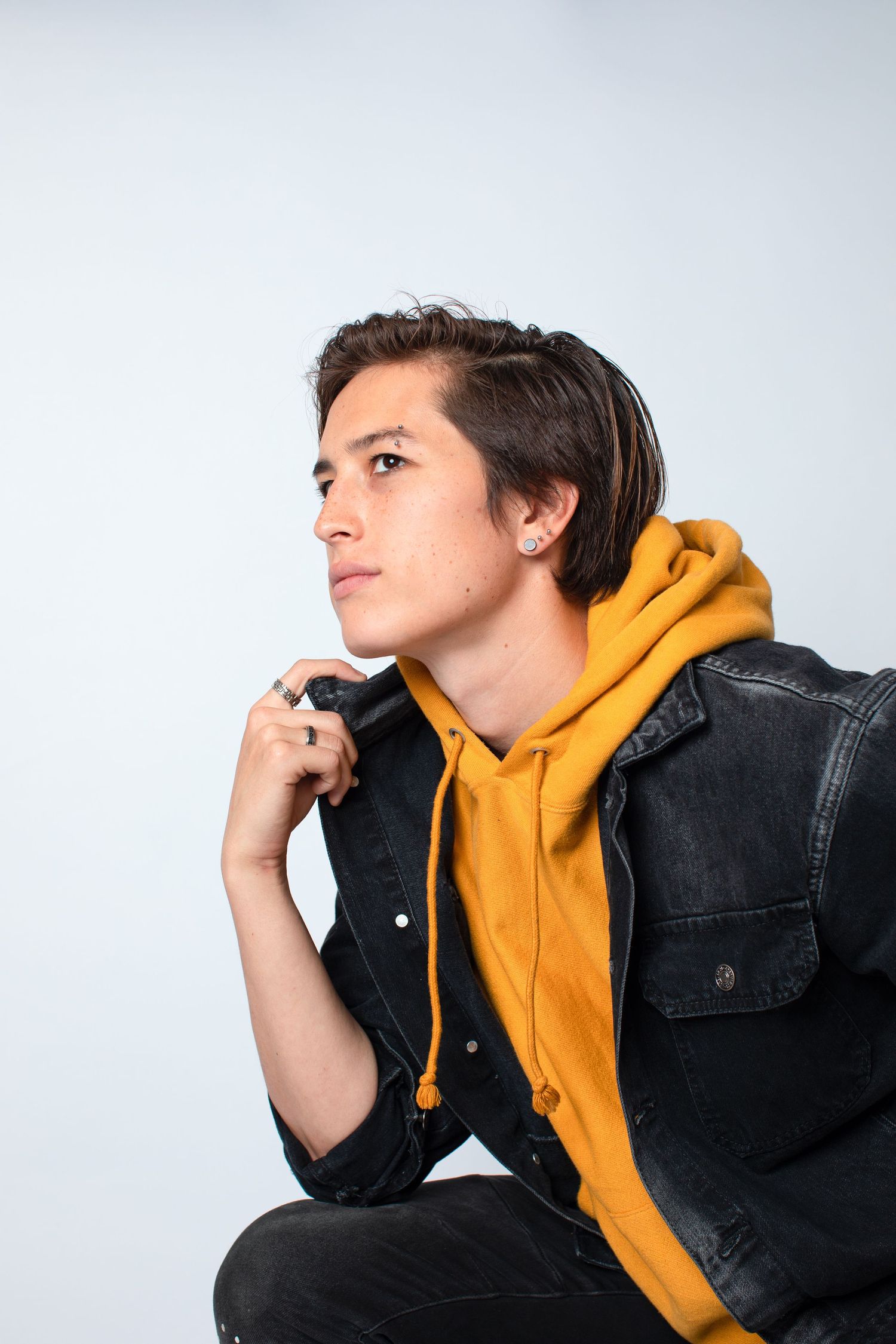 Side profile poses in yellow hoodie and black denim jacket against white background.