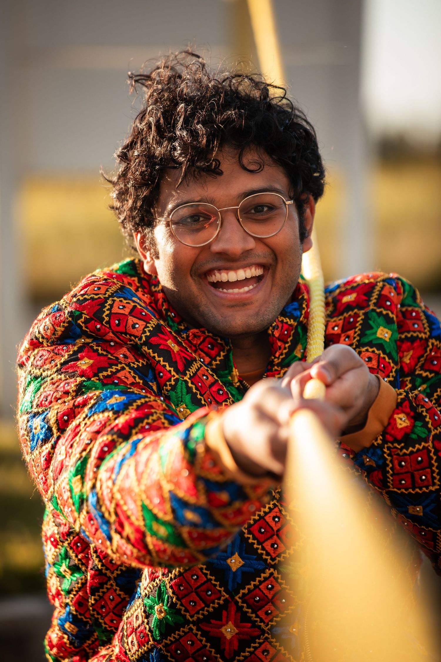 Person in colorful patterned sweater smiling and posing in a sequence of casual outdoor shots.