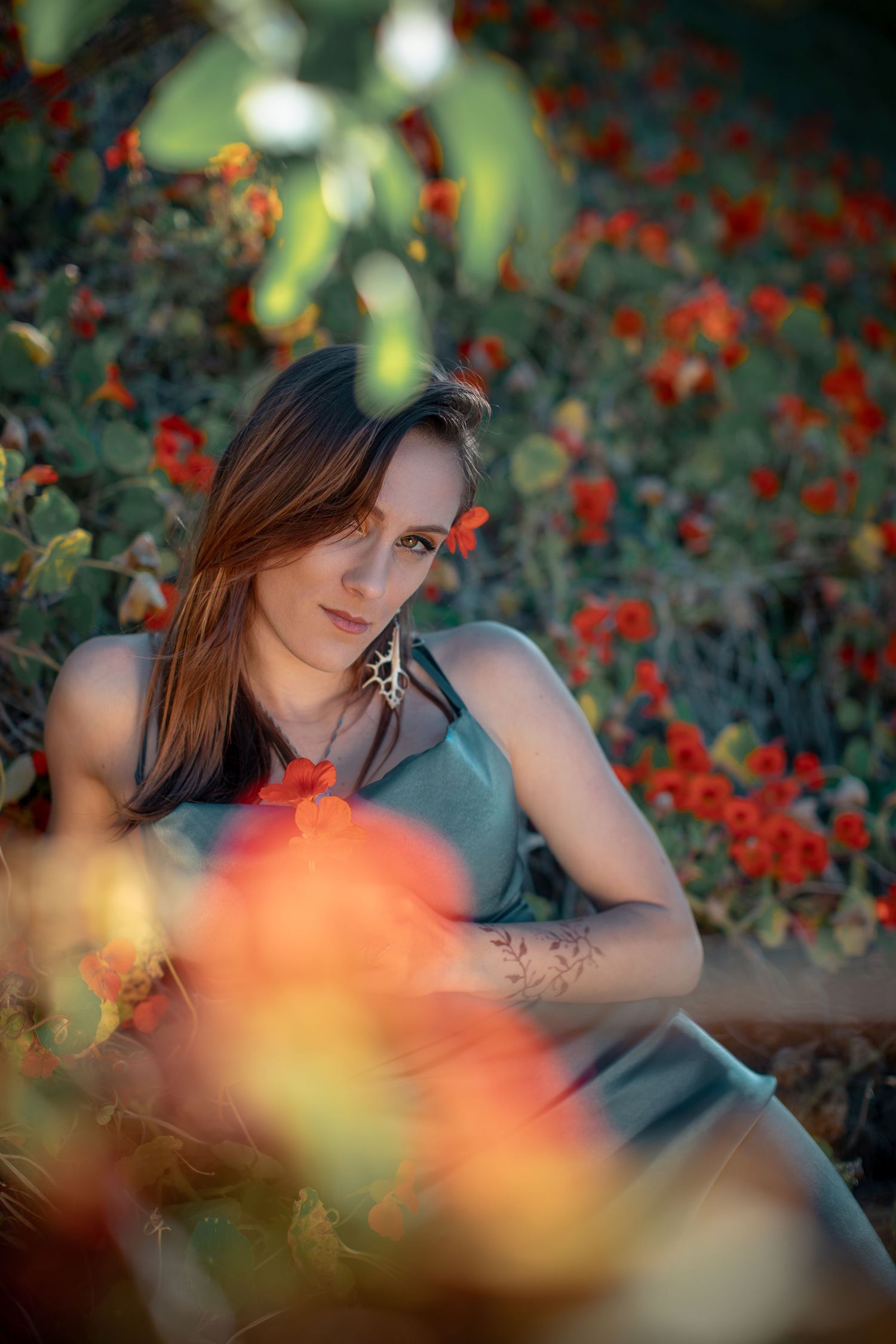 Artistic portrait among red flowers with soft focus natural lighting.