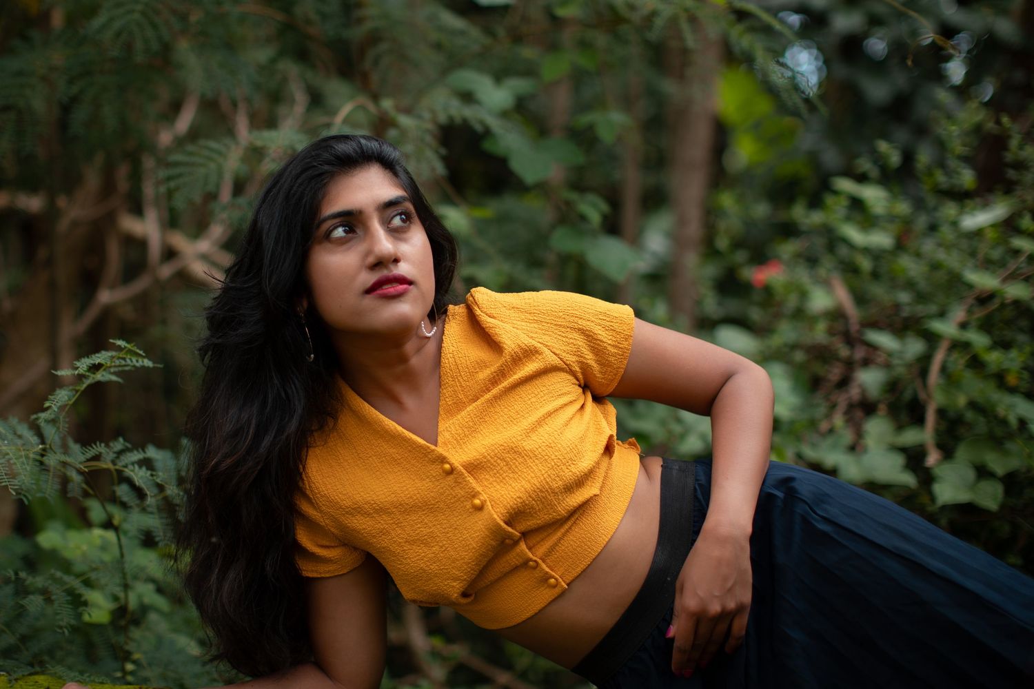 Casual outdoor portrait in yellow top against natural garden backdrop.