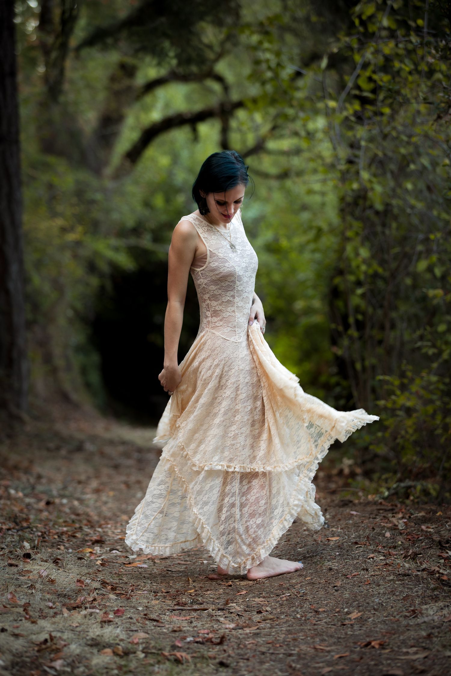 Figure in flowing white lace dress twirling on a forest path.