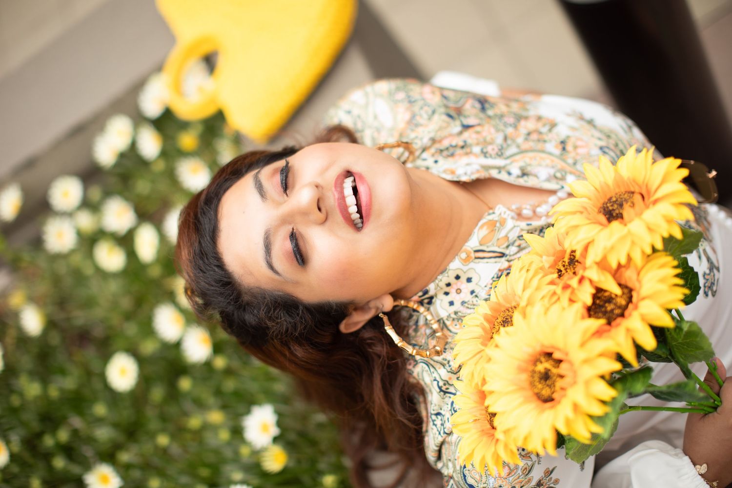 Artistic portrait with sunflowers and decorative white clothing in an outdoor garden setting.