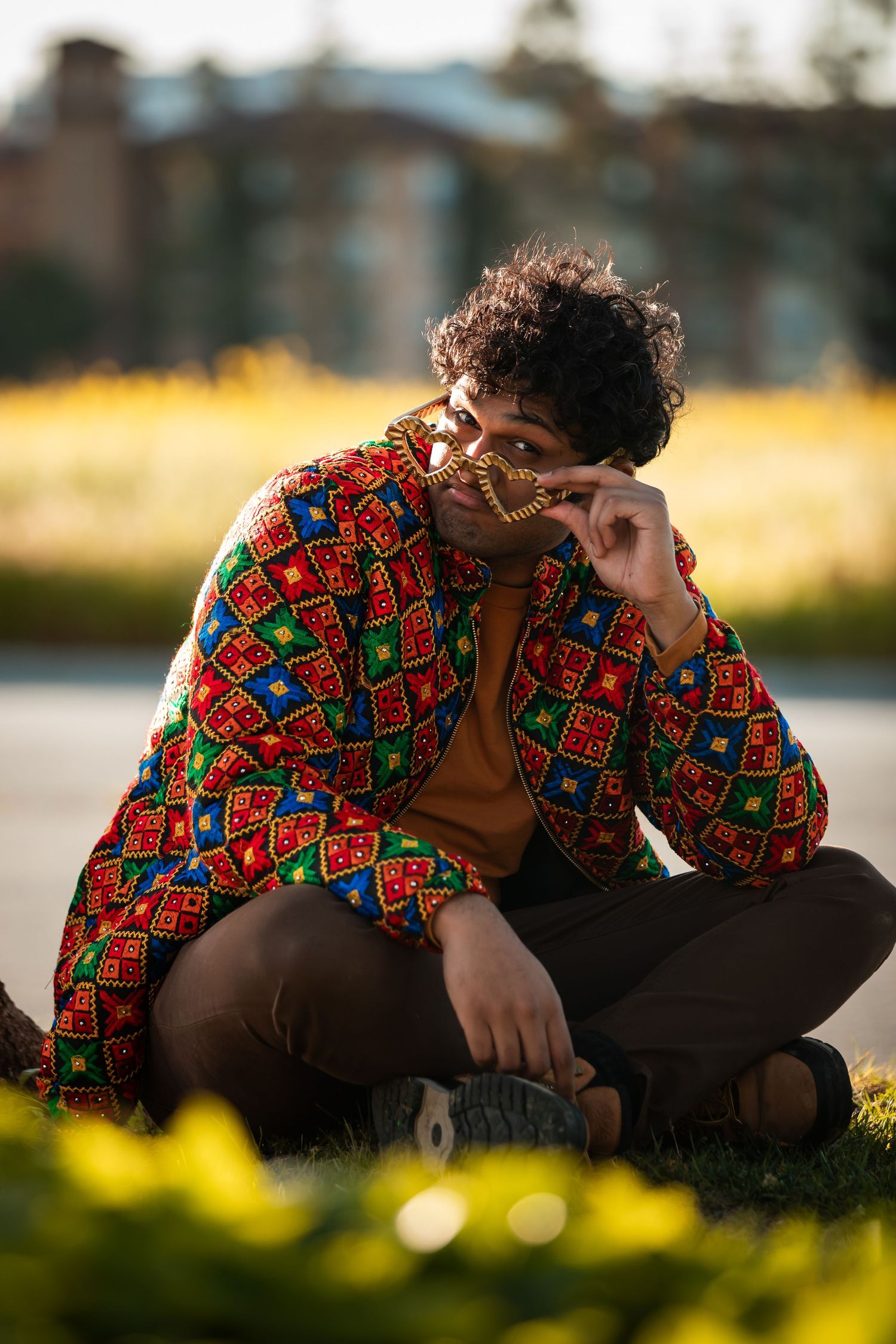 Figure wearing colorful geometric print relaxes outdoors during sunset.