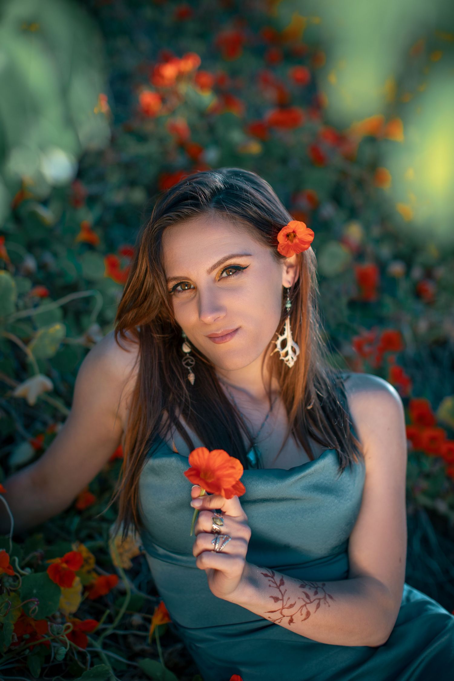 Artistic portrait among vibrant orange flowers with moody lighting and natural backdrop.