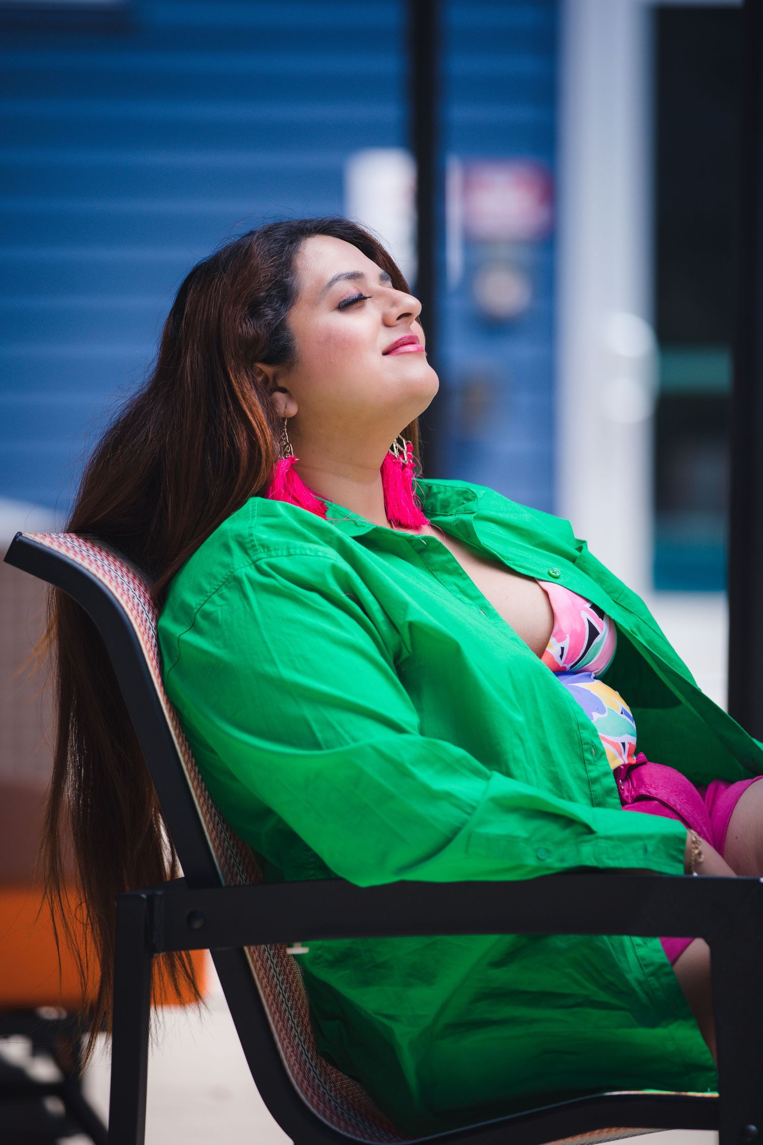 Person in bright green outfit reclines in chair against blue storage units.