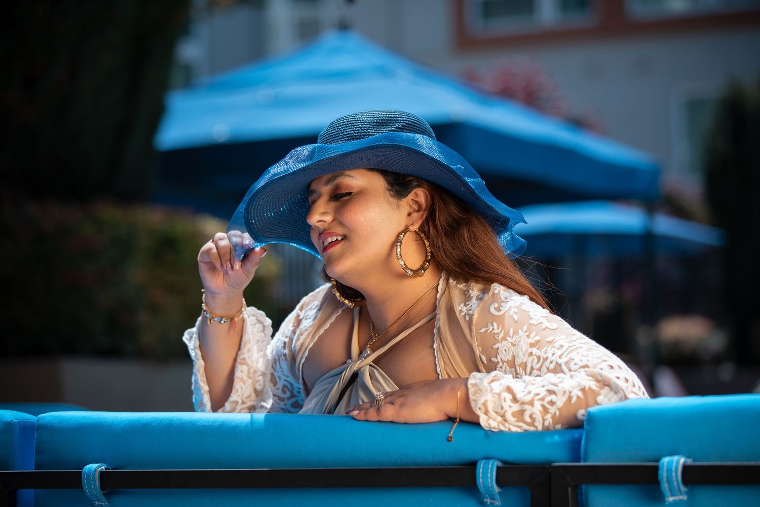 Summer poolside portrait with a blue sunhat and white lace coverup in natural lighting.