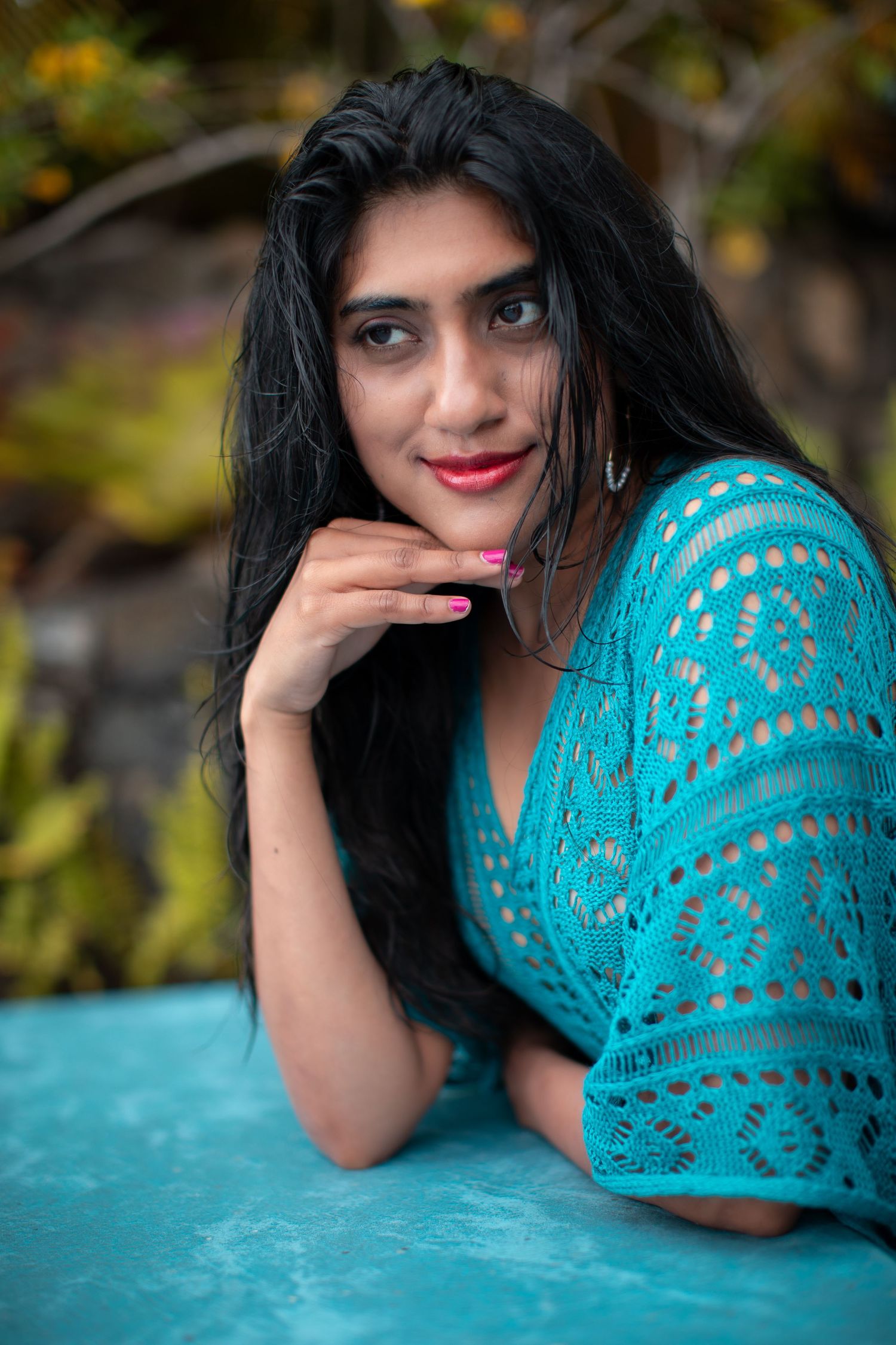 Artistic portrait with a turquoise lace top against a natural garden background.