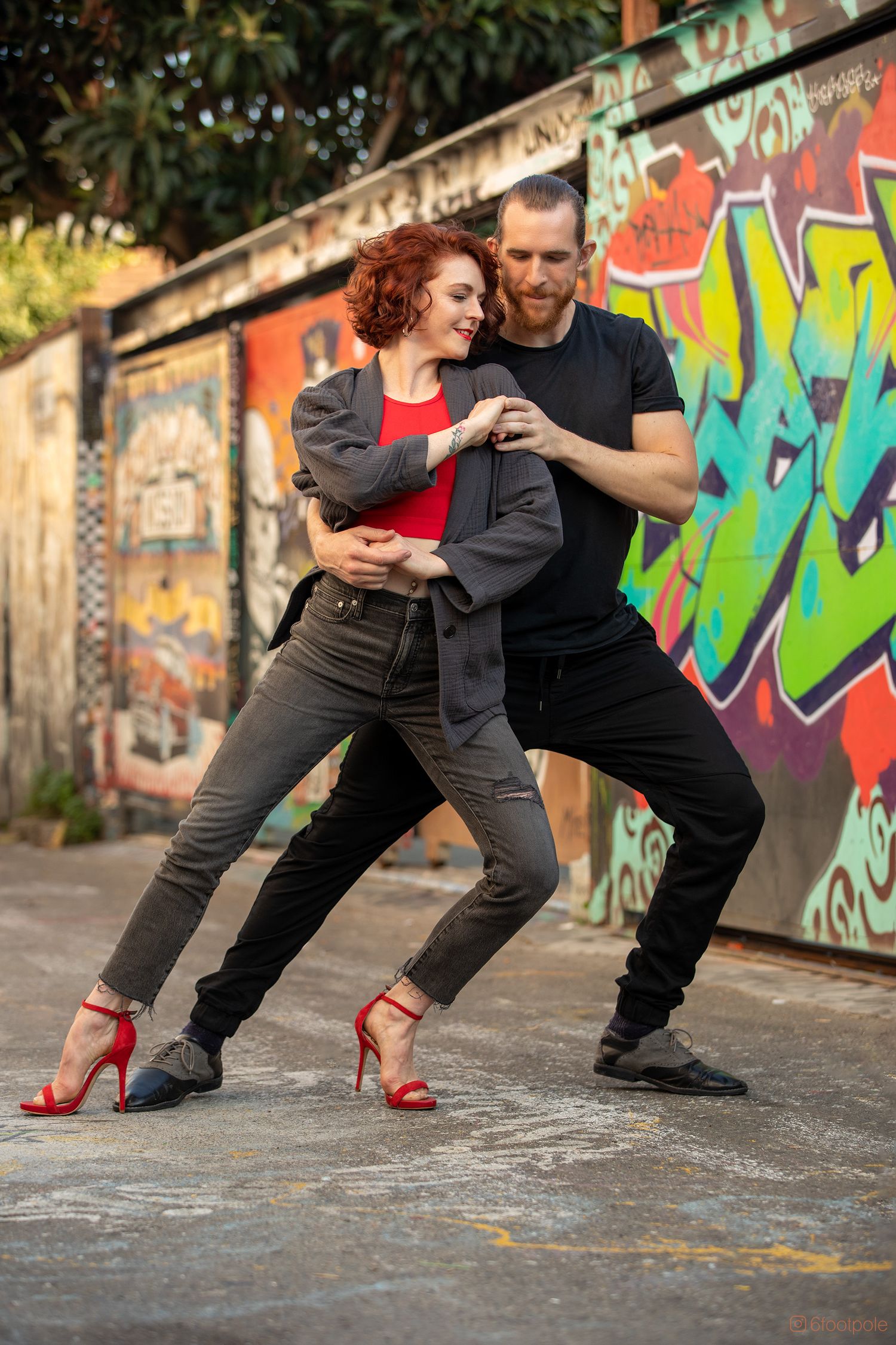 Dynamic dance pose against vibrant street art wall showcasing urban dance style and fashion.