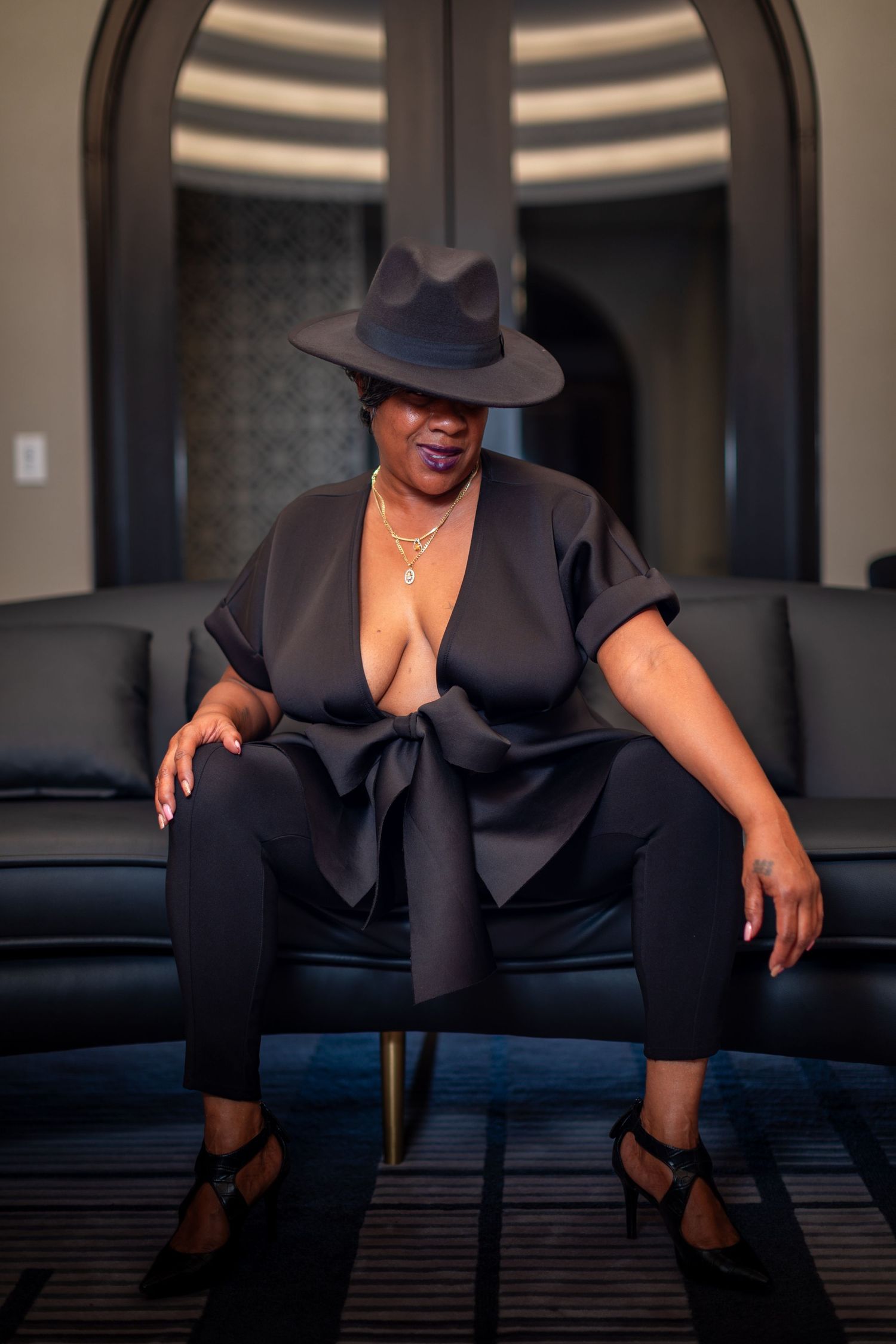 Dramatic boudoir sequence showing poses in black outfit on leather furniture.