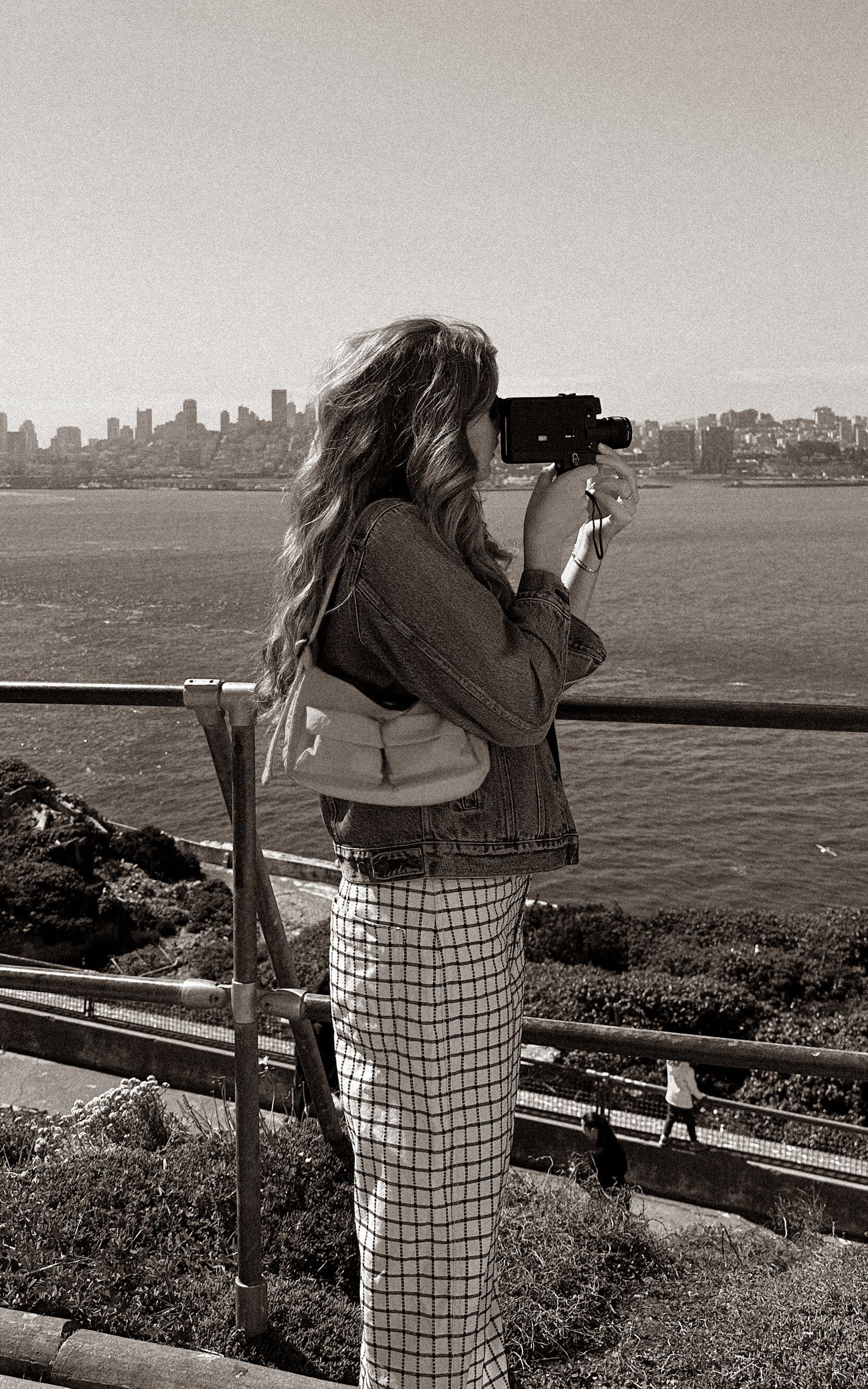 Black and white panoramic sequence of someone shooting super 8 video of a city skyline from an observation point