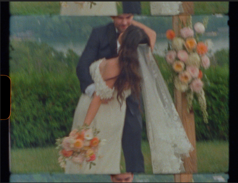 Bride and groom sharing first kiss at outdoor wedding ceremony with floral arch and bouquet.