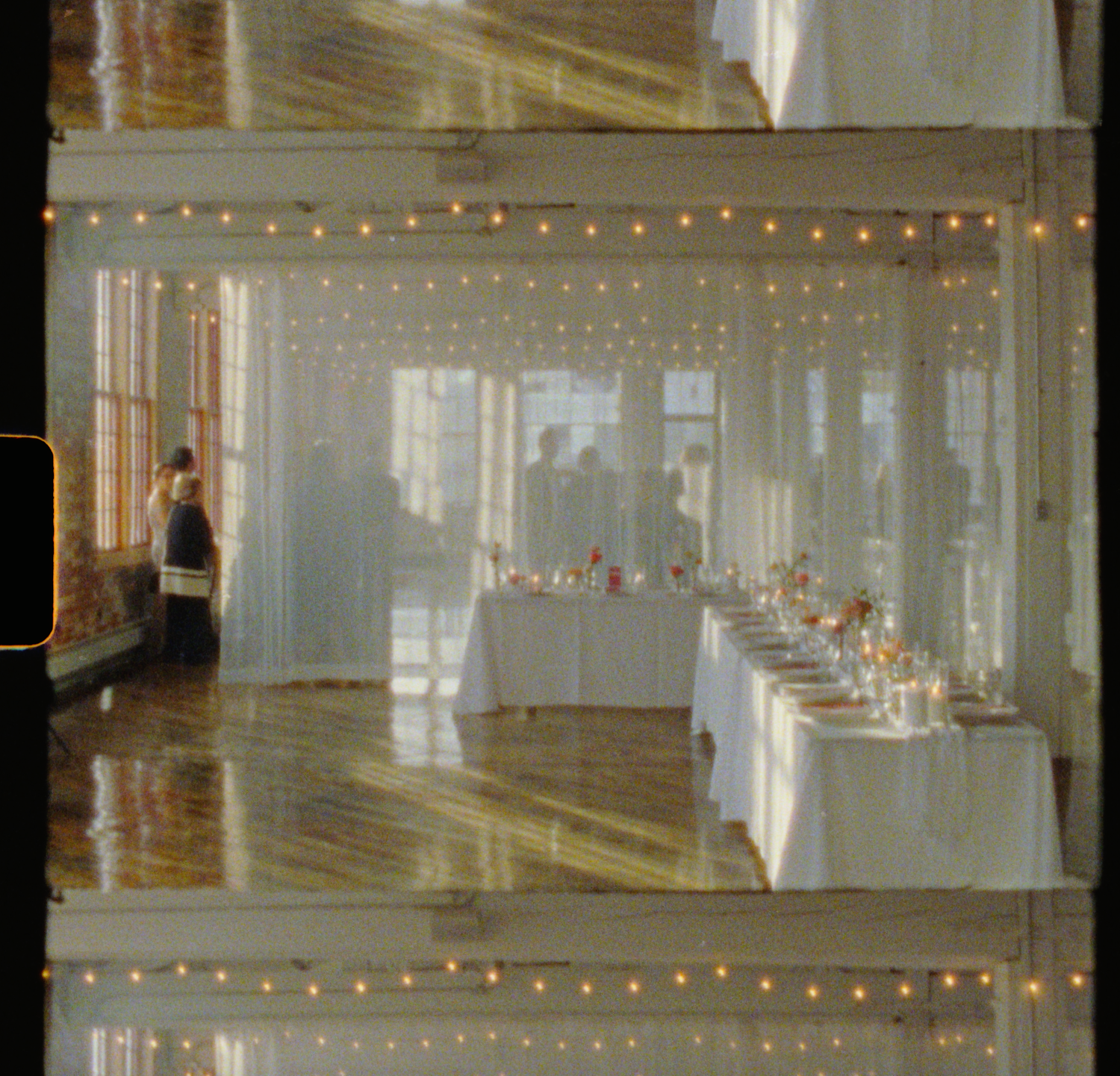 Elegant wedding reception venue with string lights, white drapes, and long dining tables set for a formal dinner celebration.