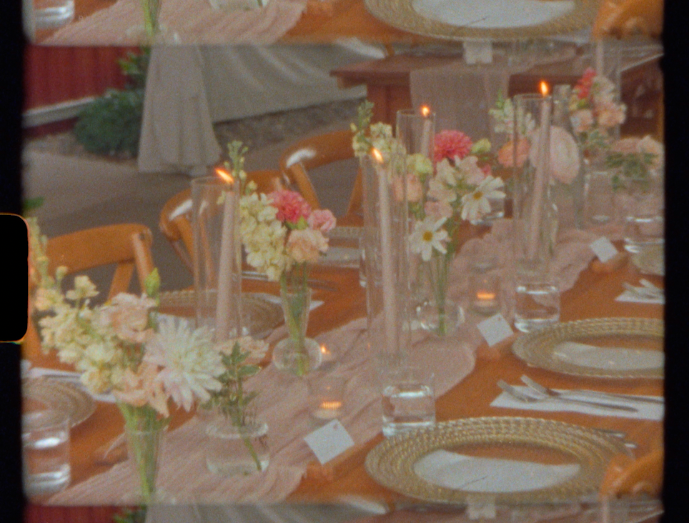 Elegant wedding reception table with floral centerpieces, pink roses, candles, gold charger plates, and a blush runner.