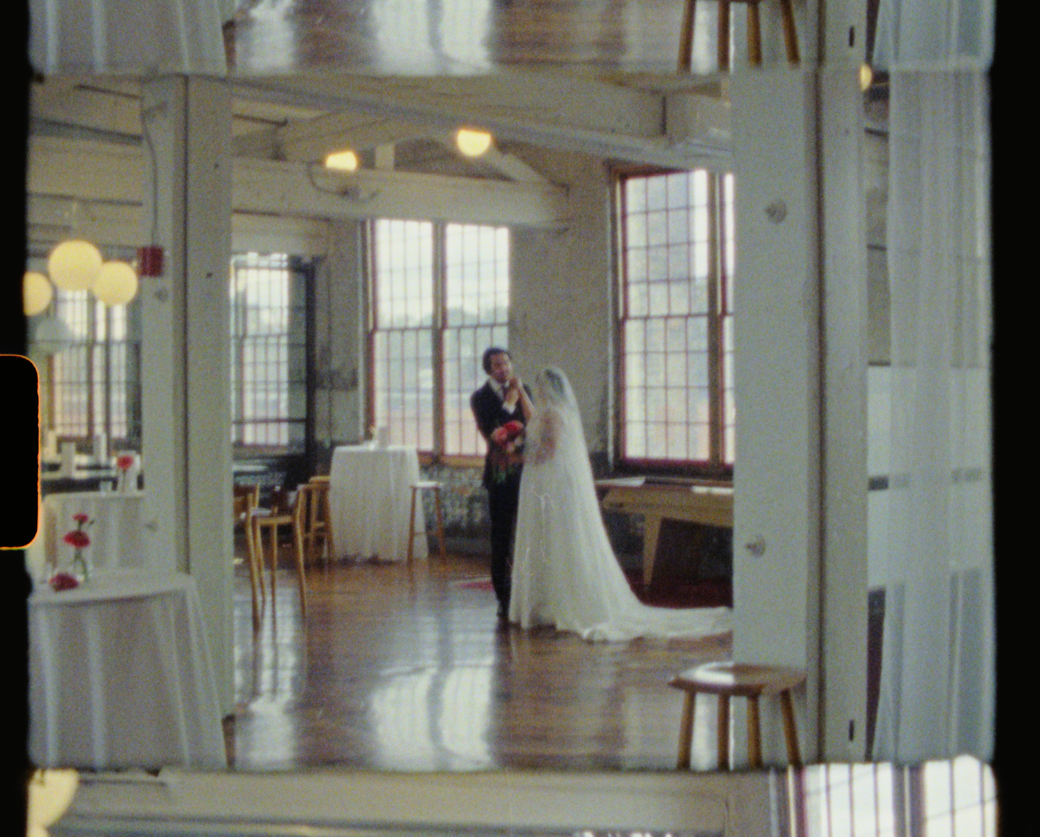 Bride and groom share first dance in elegant industrial wedding venue with hardwood floors and large windows.