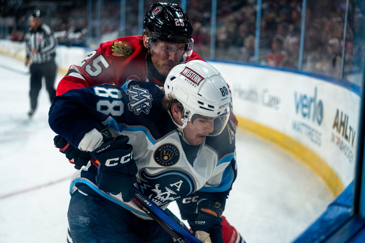 Players from Milwaukee and Iowa compete for the puck during a professional hockey match.