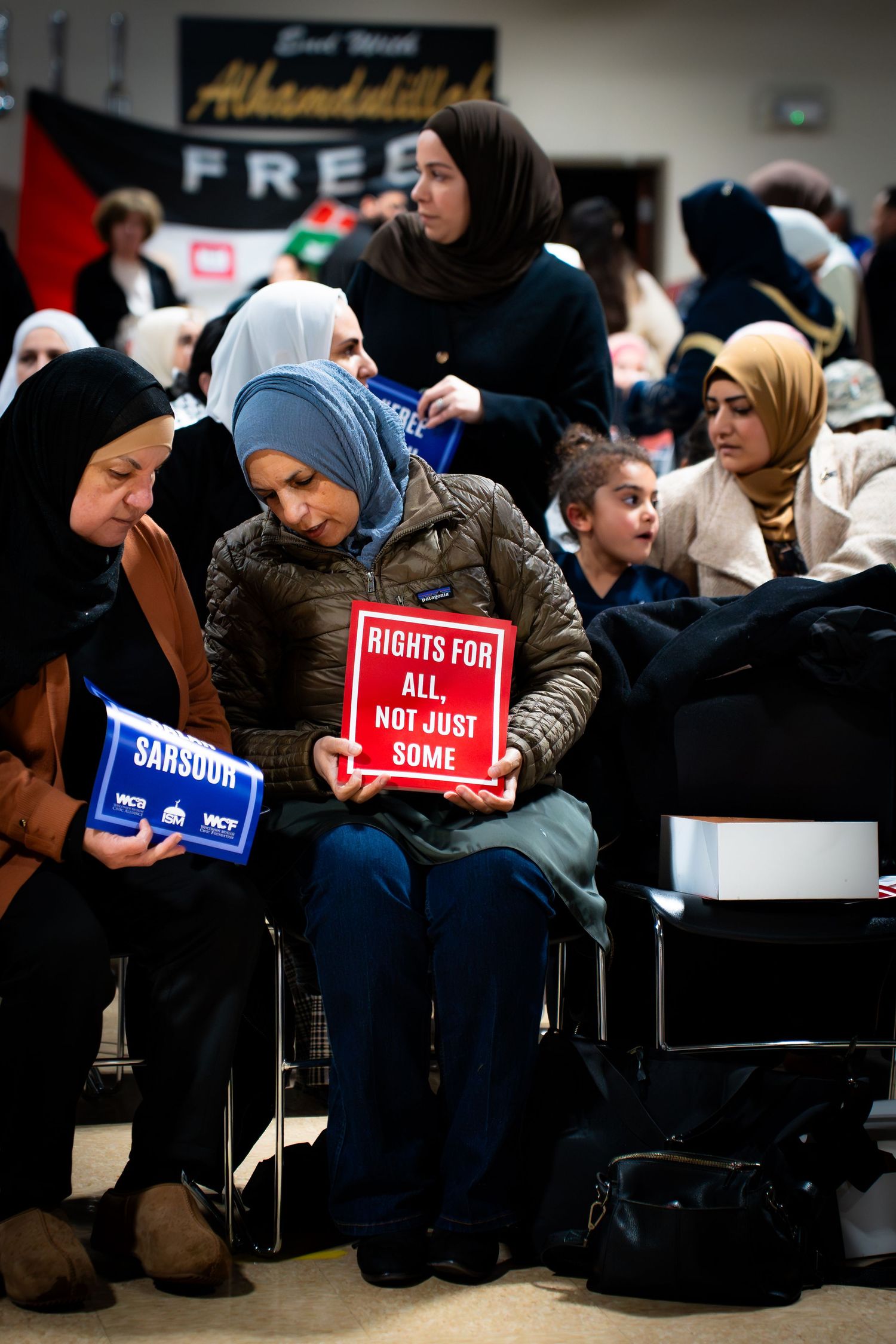 Women at a rally hold signs reading Rights For All Not Just Some and Sarsour at a civil rights protest event.